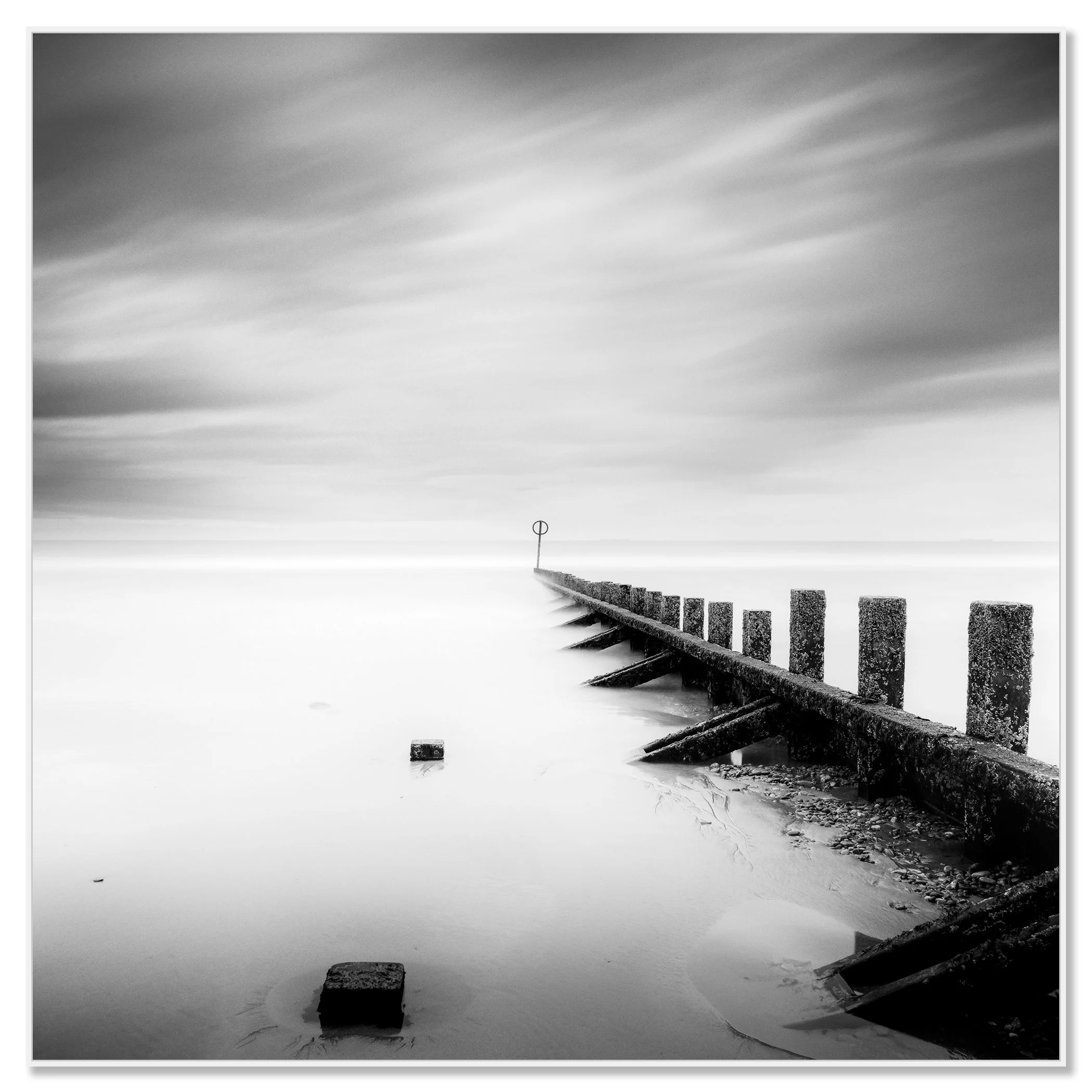 © 2012 Gerald Berghammer - Black and white landscape photography. A wooden wave breaker extending into a calm body of water, with a circular marker at the end. Chromaluxe framed white