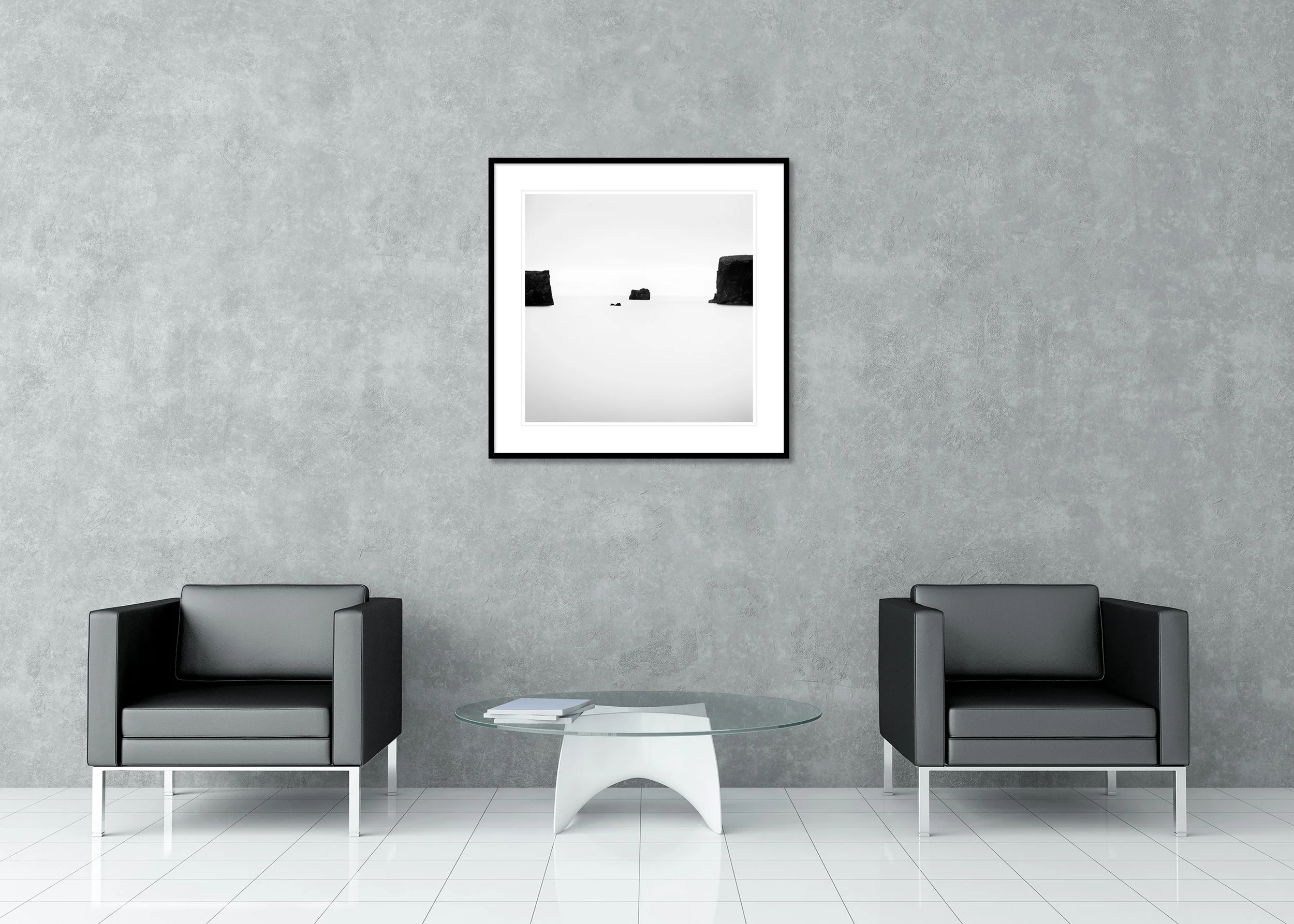 Minimalist black and white photograph of ocean water with three dark rock formations and distant sea cliffs, archival pigment print in a classic frame with passe-partout.