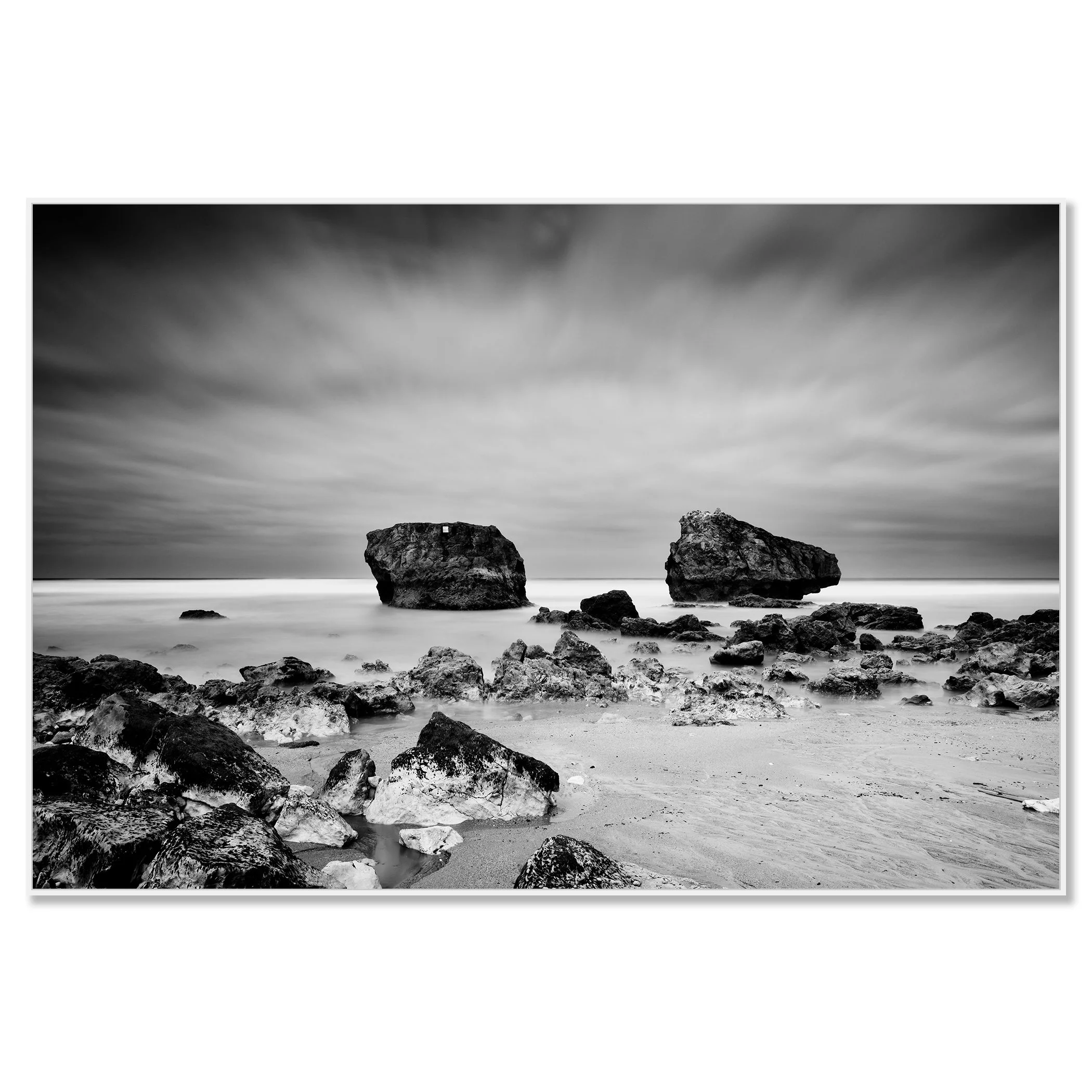 Black and white landscape photo of a rocky beach with two sea stacks, cloudy sky and smooth ocean water – framed ArtBox white