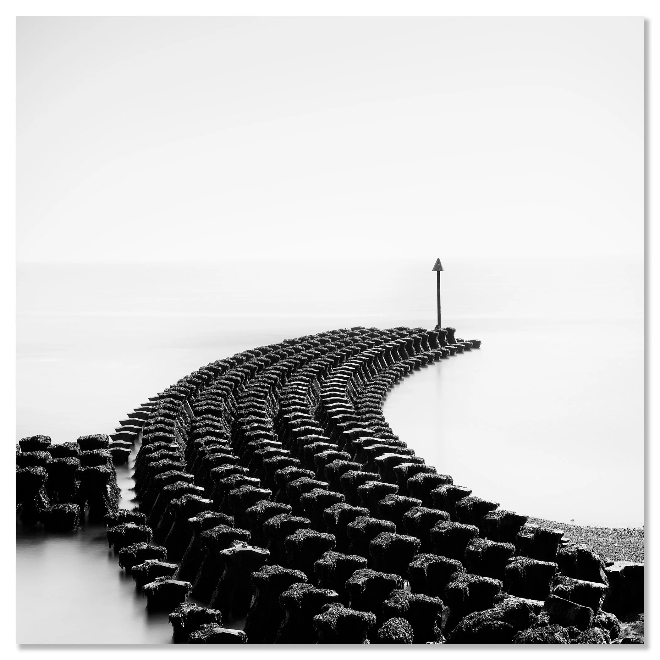 Black and white seascape with curved timber groynes leading to a coastal warning sign – dibond frameless