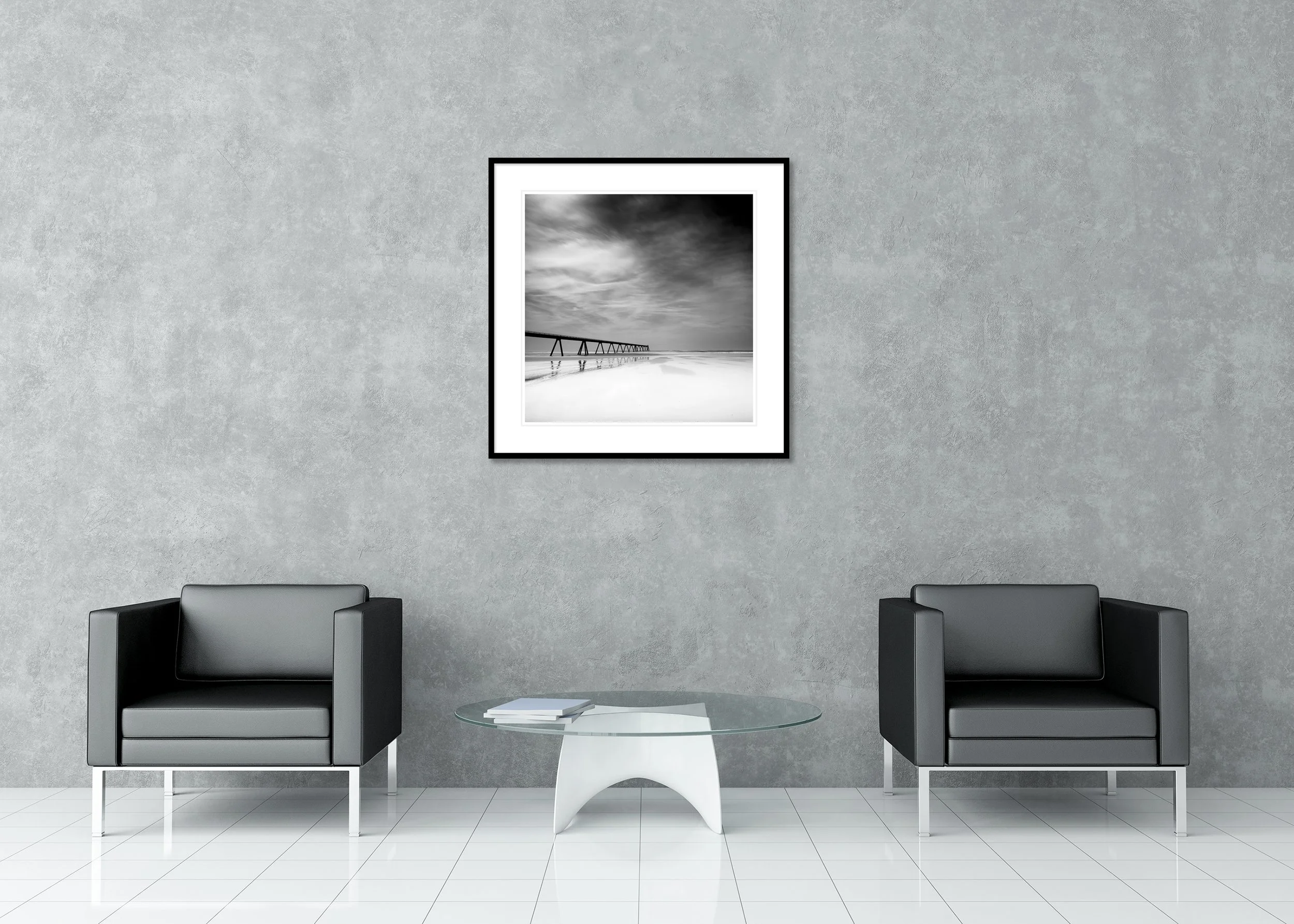 Black-and-white seascape photograph with pier and wide beach, shown as an archival pigment print in a classic frame with mount