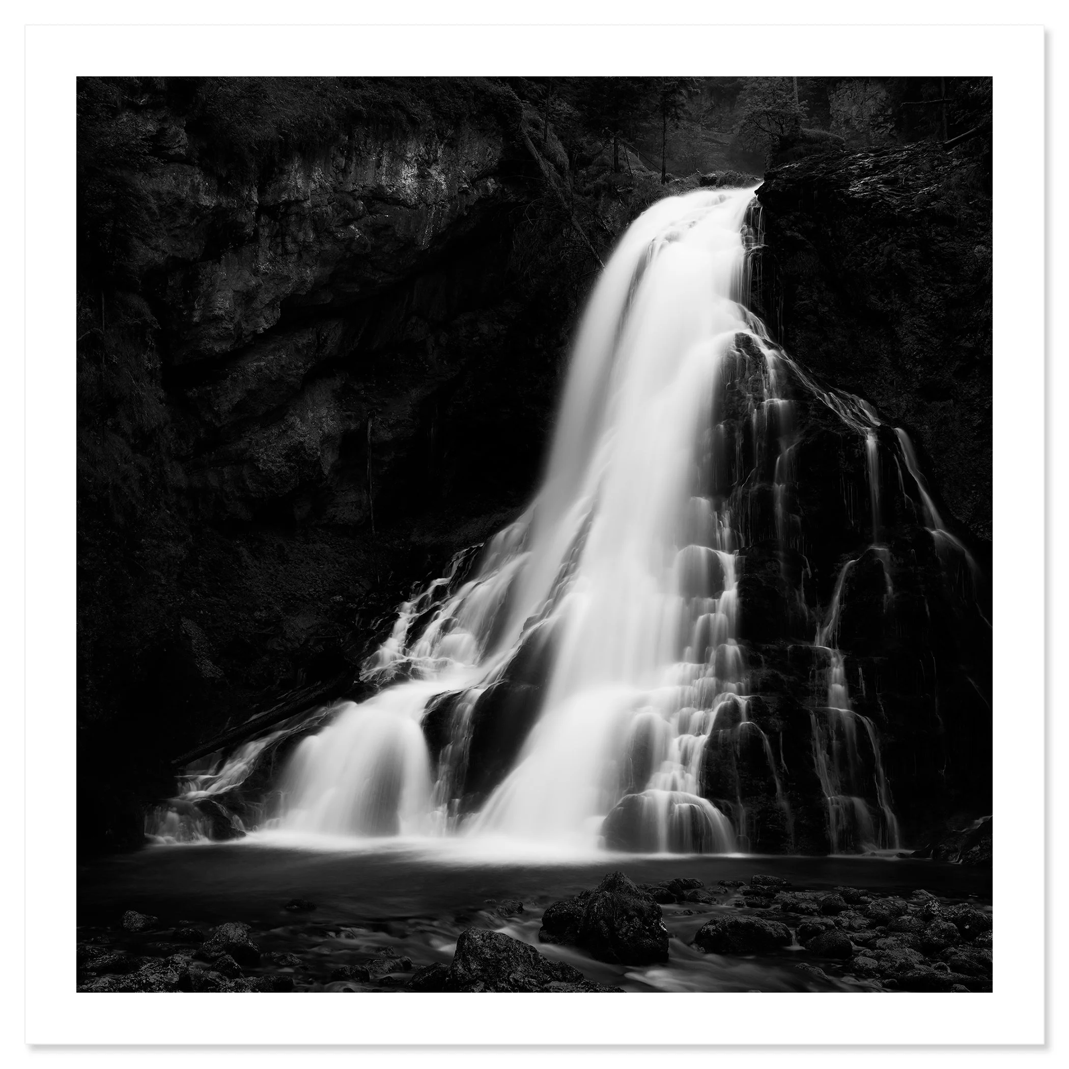Black-and-white photograph of a waterfall cascading down a rocky cliff into a pool below, Print only
