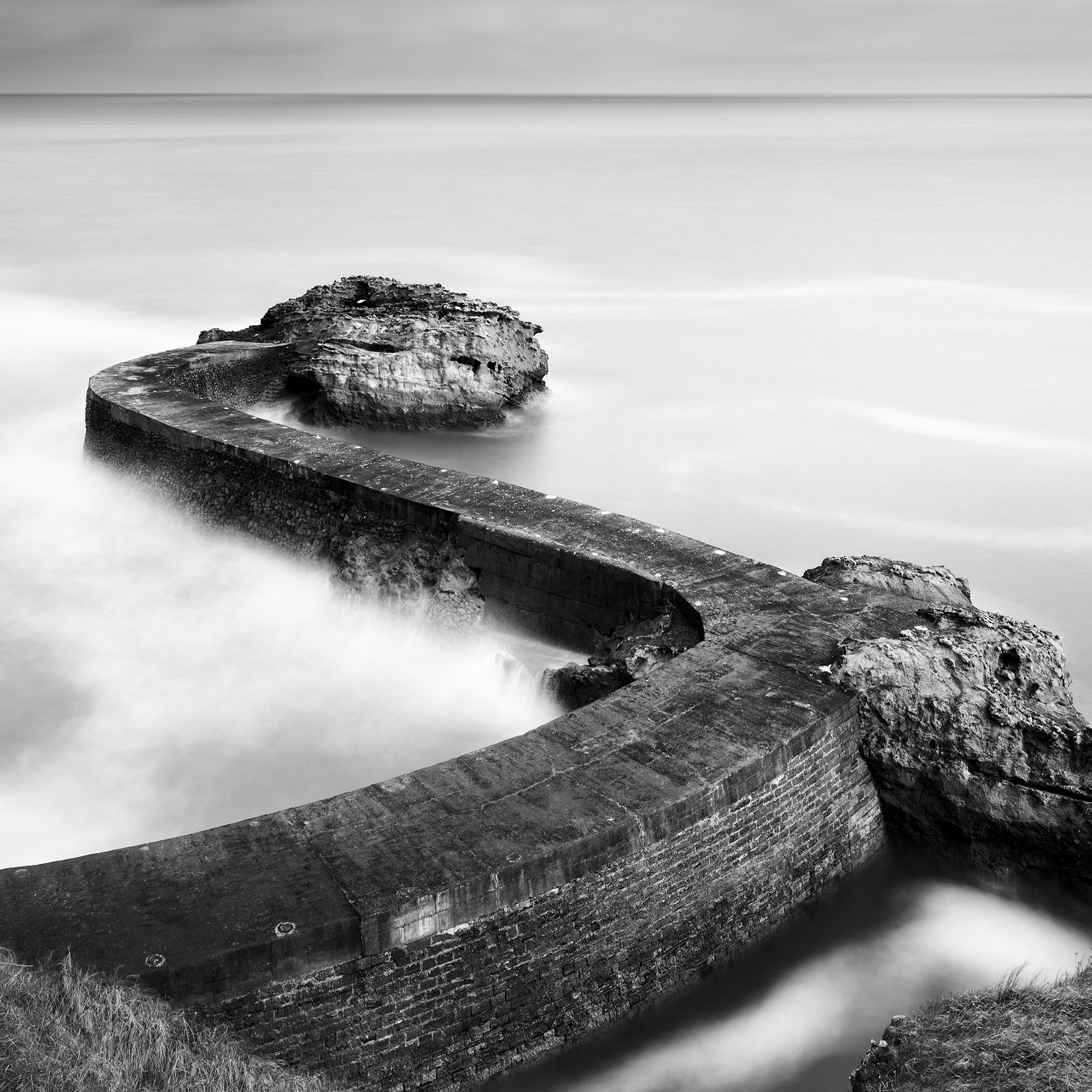 Breakwater Pier Study 1 by Gerald Berghammer, detail of soft long-exposure Atlantic waters and dramatic cloud formations in a minimalist black-and-white seascape.