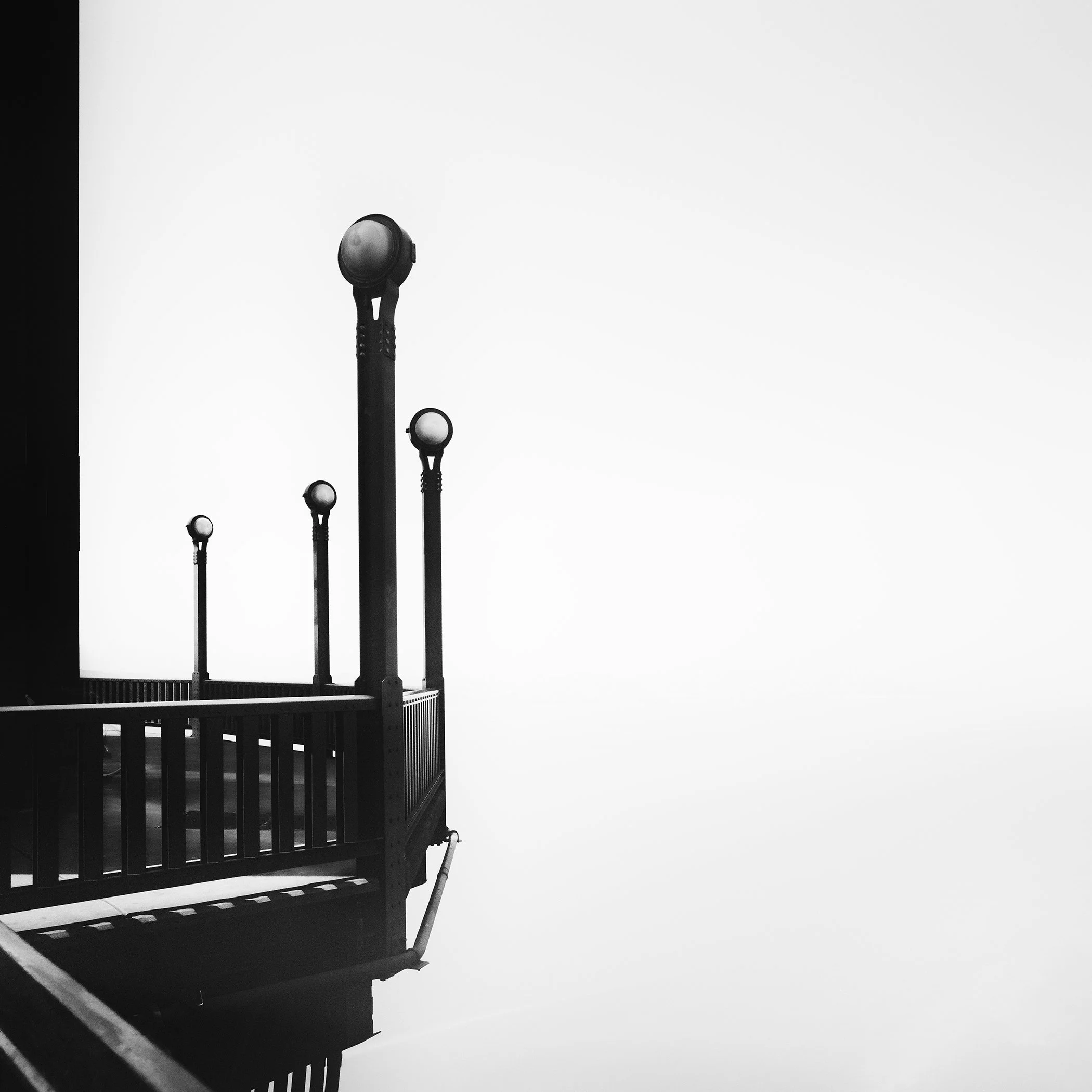 Architectural detail of the Golden Gate Bridge with silhouetted lamps against a bright sky, photographed by Gerald Berghammer.