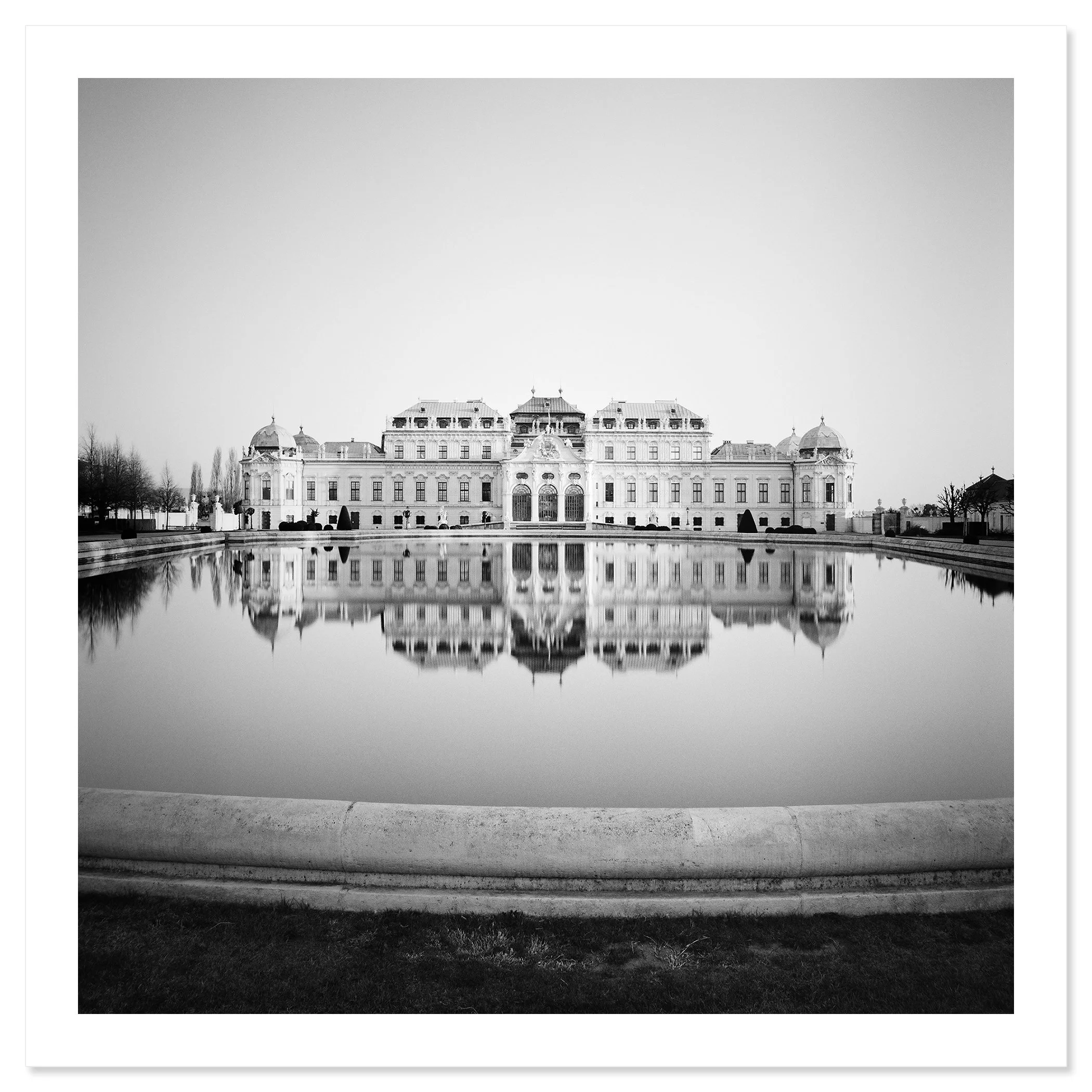 Gerald Berghammer - Black and white cityscape photography. A grand, historical building with ornate architecture reflected in a large, calm body of water. Fine art print only