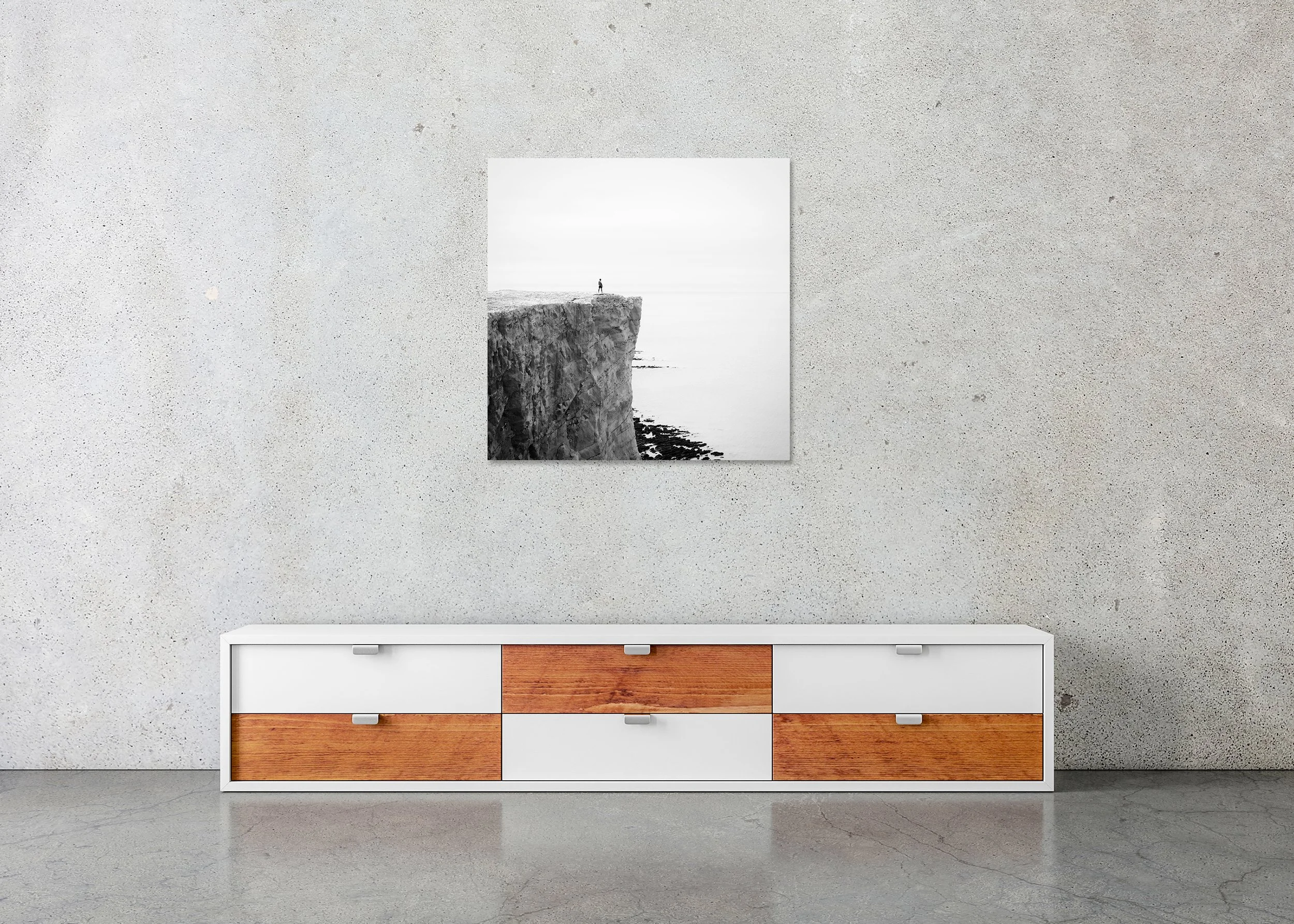 Minimalist black-and-white landscape photo of a lone person on a cliff above the ocean, evoking solitude, scale, and reflection. ChromaLuxe Metal Print – Frameless