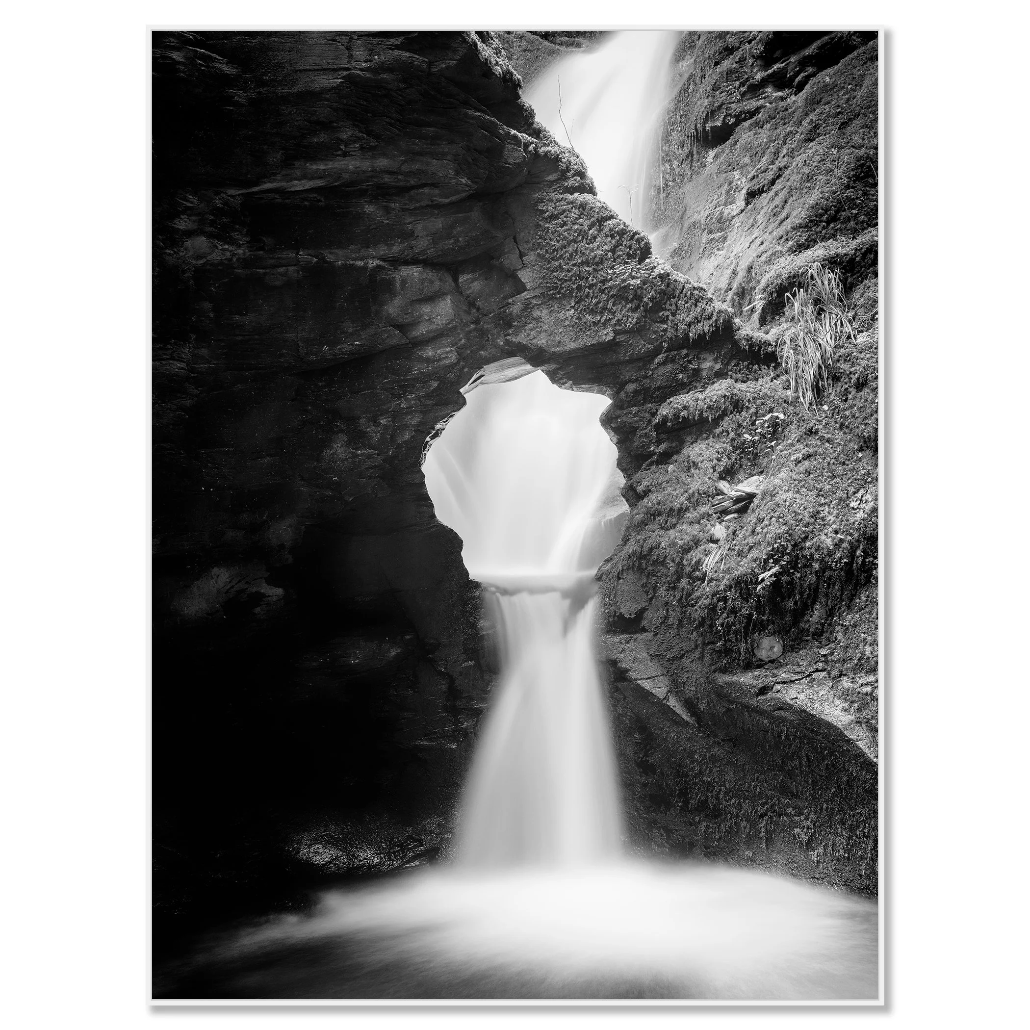 Fine art black and white waterfall print with silky water, rugged rock formations and moss-covered cliffs – framed ArtBox white