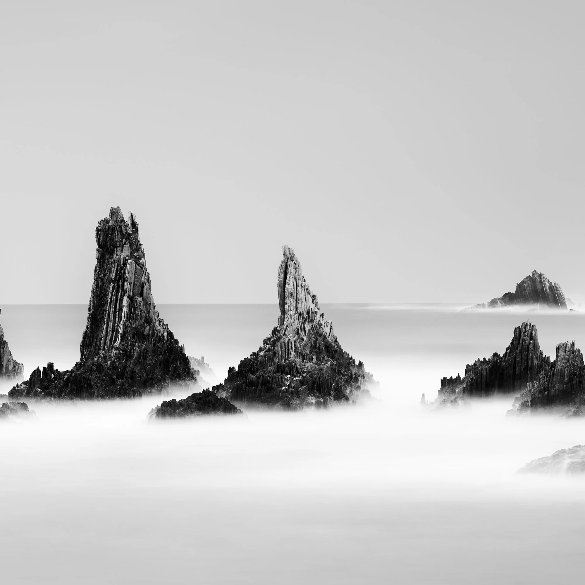 Detail of sculptural rock formations and smooth long-exposure water in Rocky Peaks Panorama, Study 2, Spain, by Gerald Berghammer.