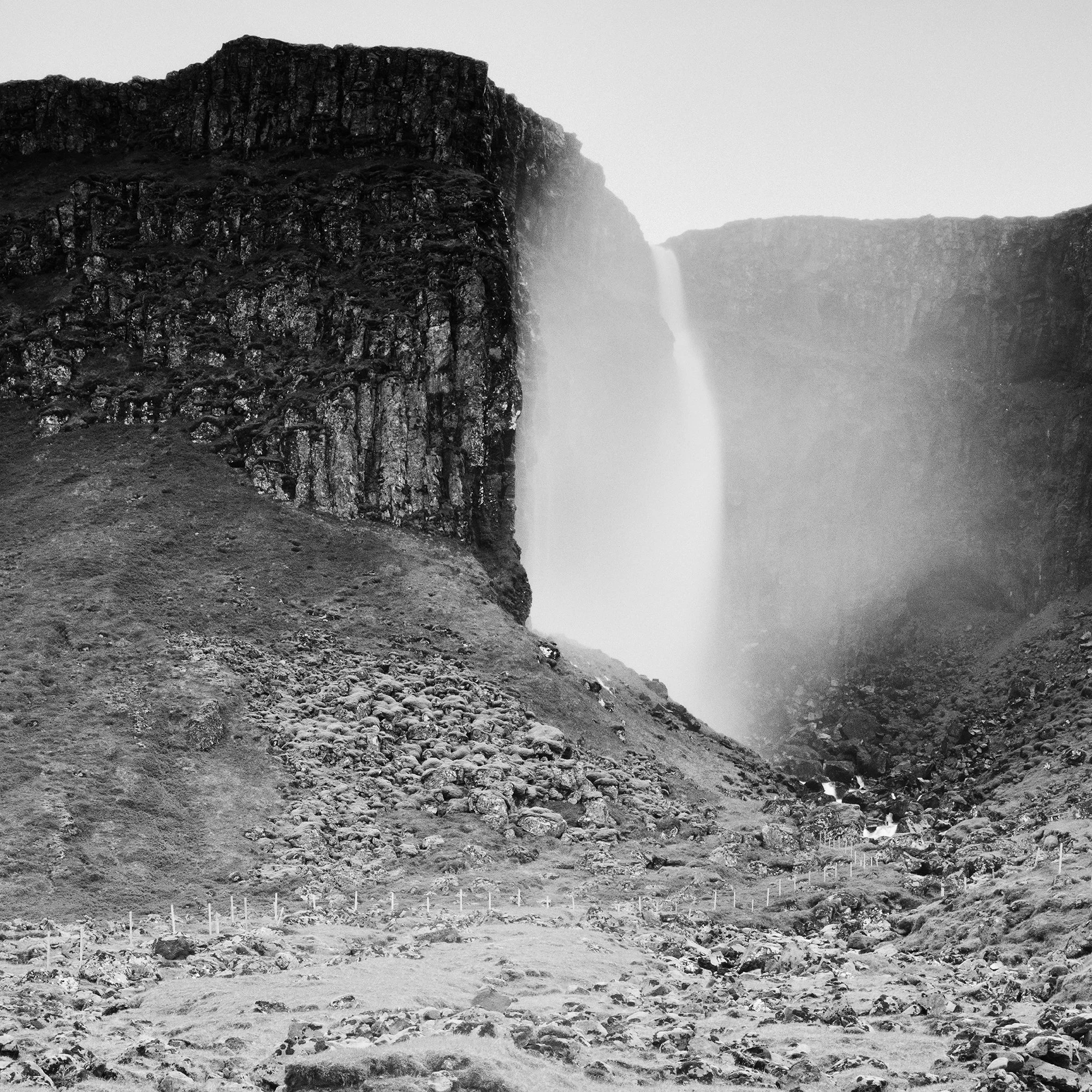 Gerald Berghammer - Black and white landscape photography. A waterfall cascading down a rocky cliff into a stream surrounded by rocks and rugged terrain. Print detail 3