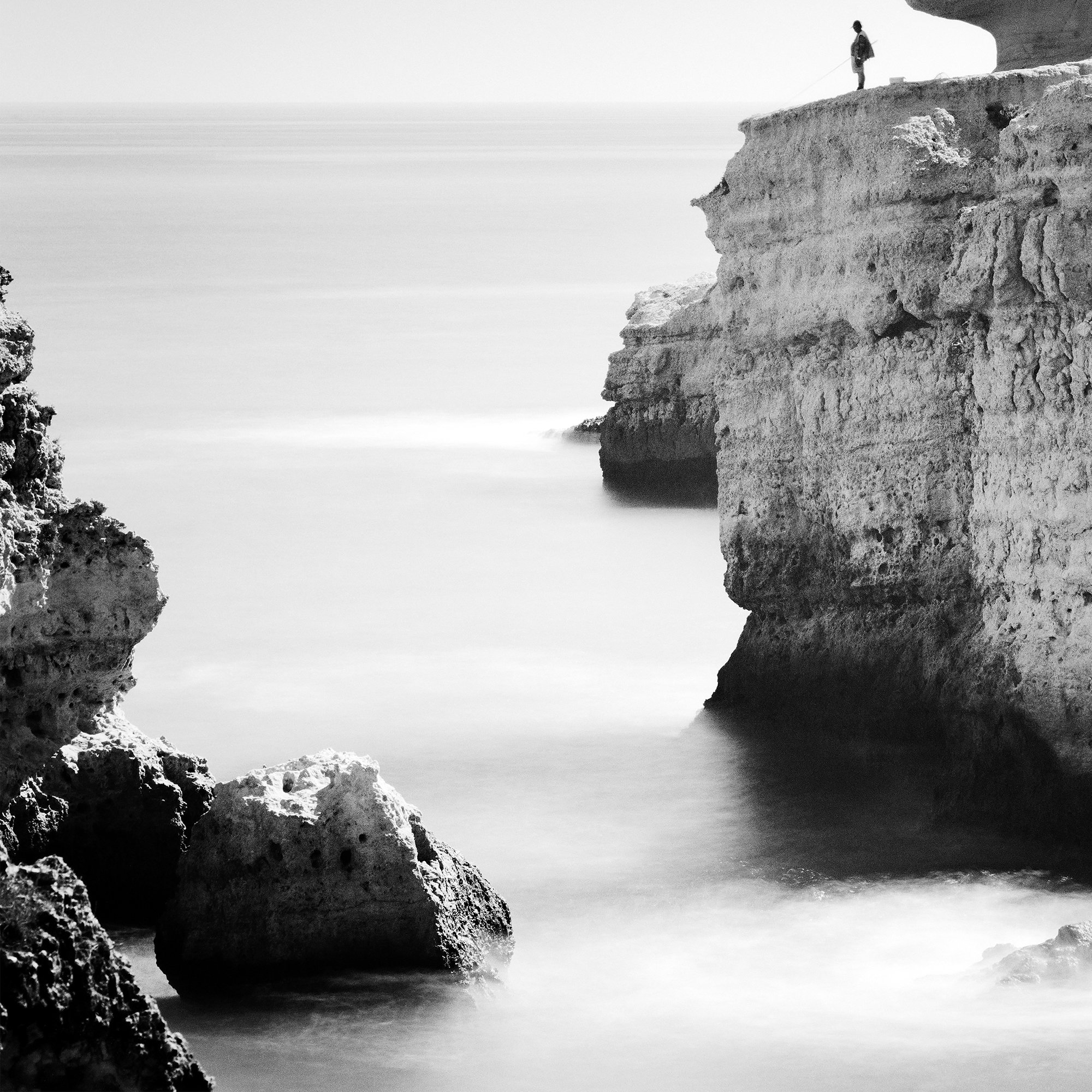 Close-up of Rock Fishing Study 1 showing the solitary fisherman and rugged Portuguese coastal cliffs. Photo by Gerald Berghammer.