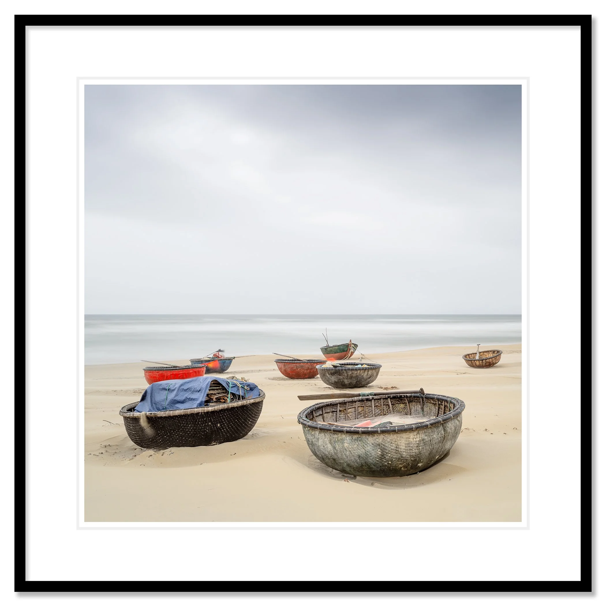 Gerald Berghammer - Color landscape photography. Several small boats resting on a sandy beach with calm ocean water under an overcast sky. Classic framed black