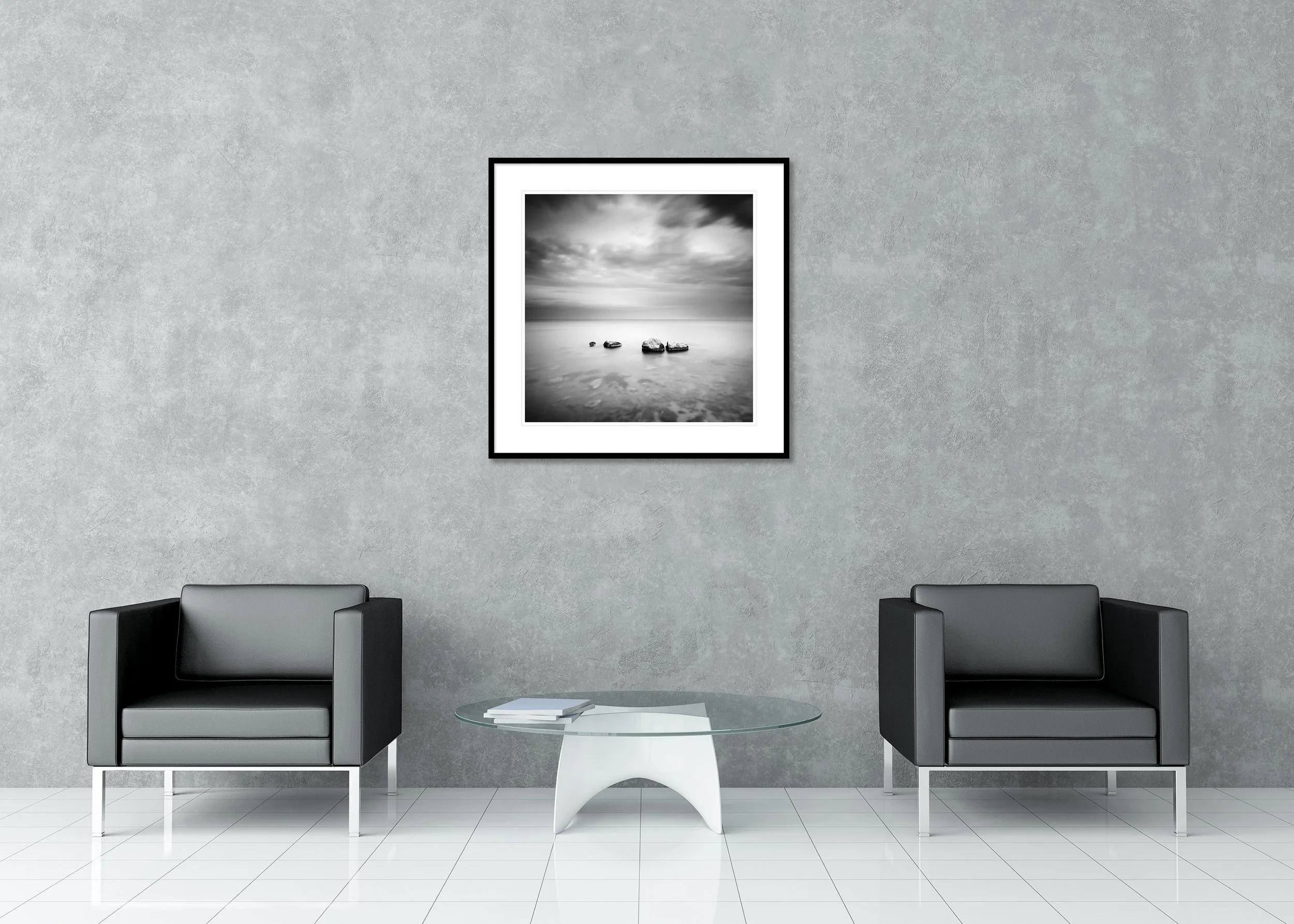 Black and white long-exposure seascape with four rocks in calm water, cloudy sky, archival pigment print in framed presentation.