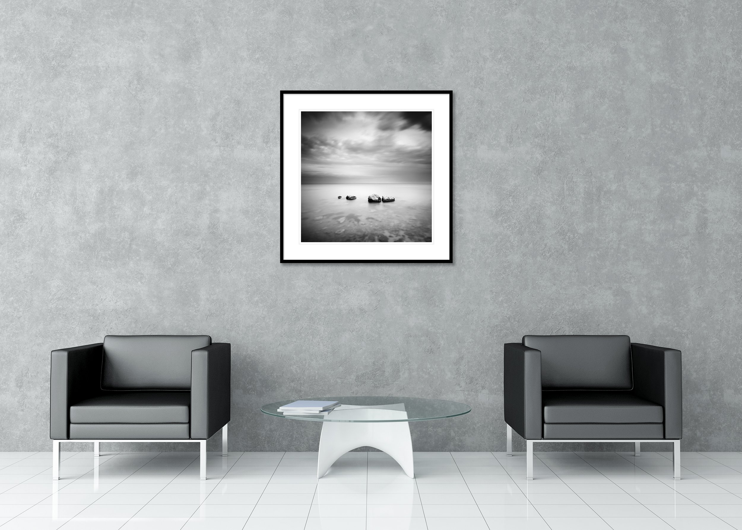 Black-and-white long-exposure seascape with four rocks in calm water under a cloudy sky, archival pigment print in a classic frame with mount.