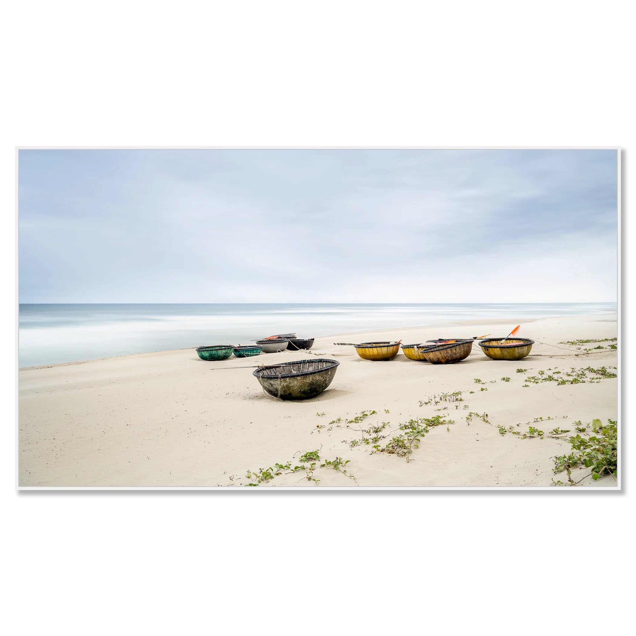 Colorful coconut boats on sandy beach in Vietnam, calm sea, sparse green vegetation under cloudy sky – framed ArtBox white
