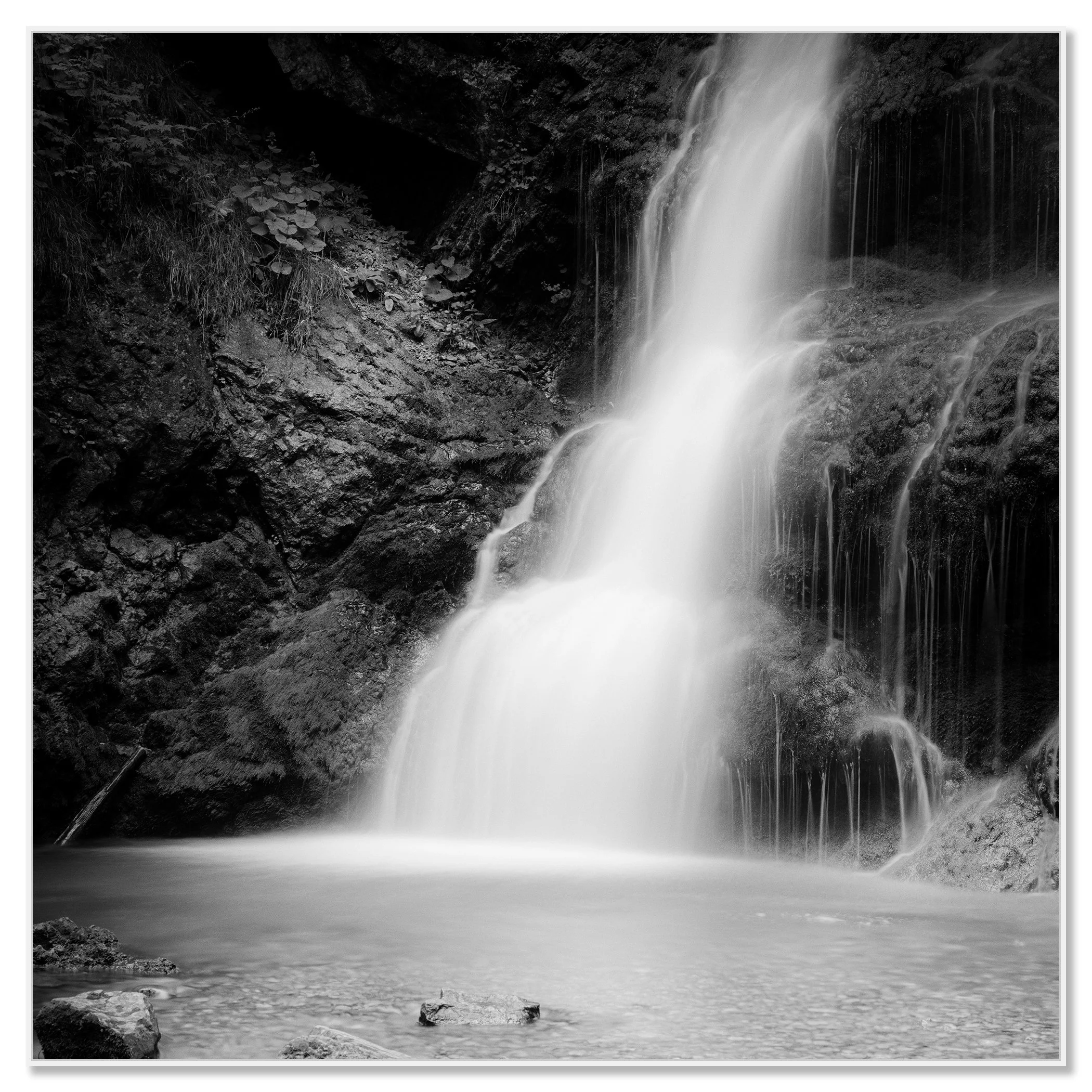 © 2020 Gerald Berghammer - Black and white long exposure abstract photography.  Waterfall descending into a calm pool surrounded by rocky terrain. Chromaluxe framed white