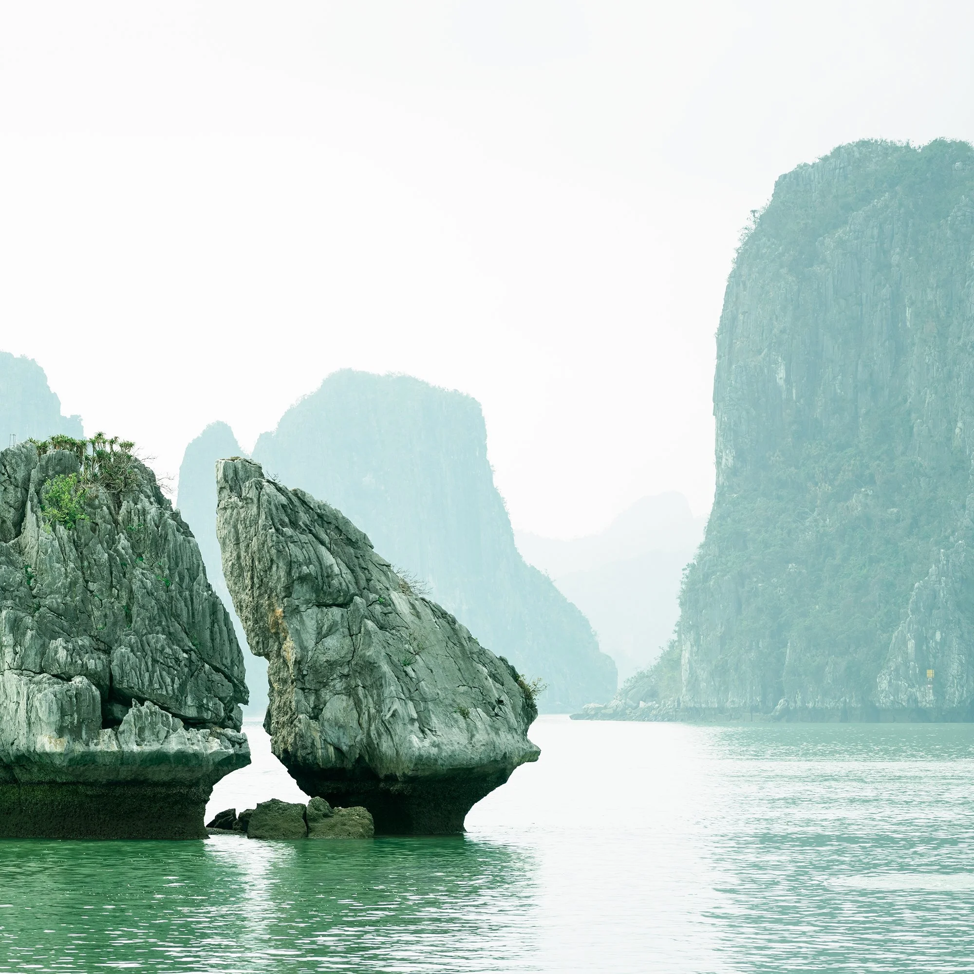 Gerald Berghammer - Color seascape photography. Large rocks rising from the water with, surrounded by calm water and distant limestone cliffs and islands. Print detail 2