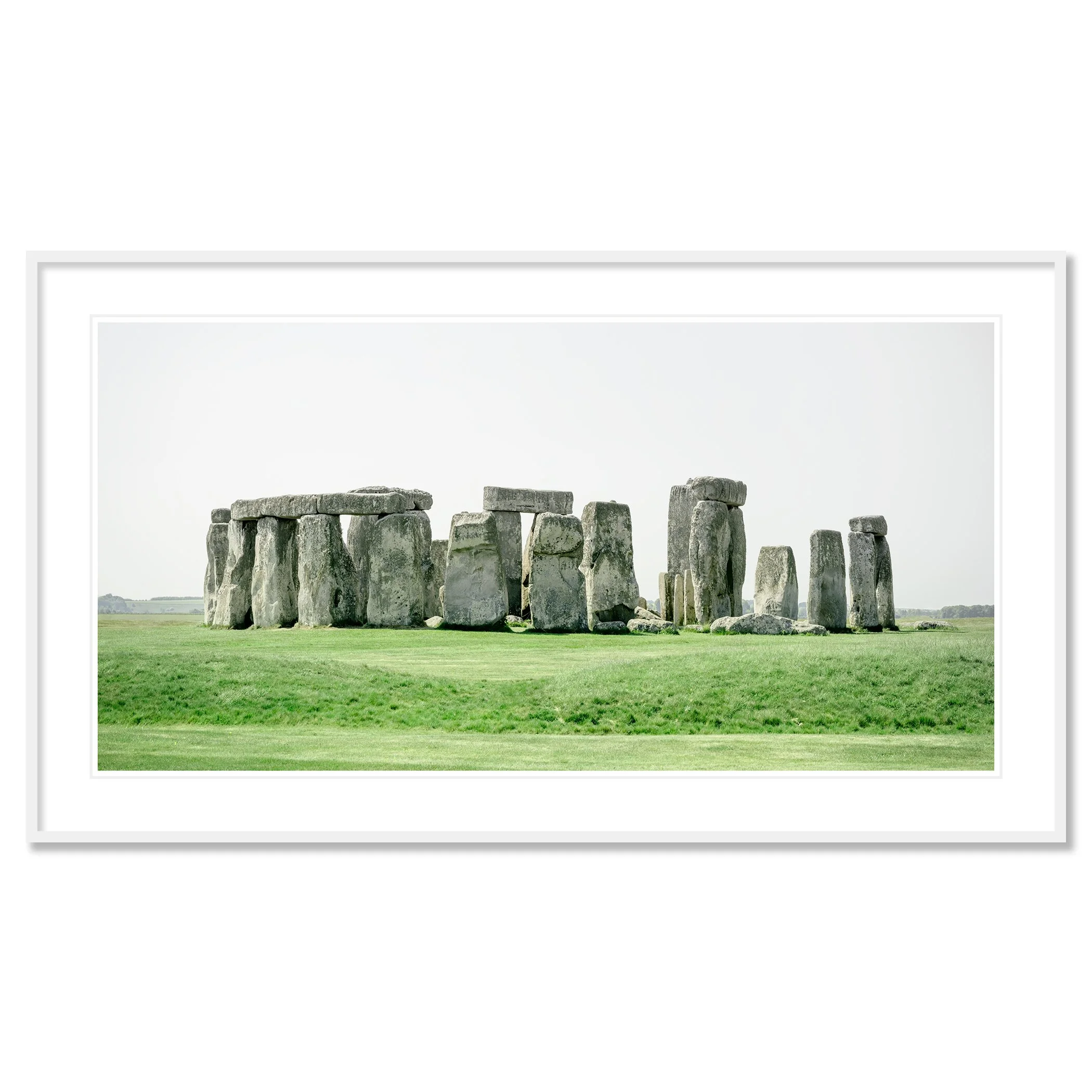 Gerald Berghammer - Color landscape panorama photography. Historic Stonehenge monument with large standing stones on a grassy field under a gray sky. Classic framed white