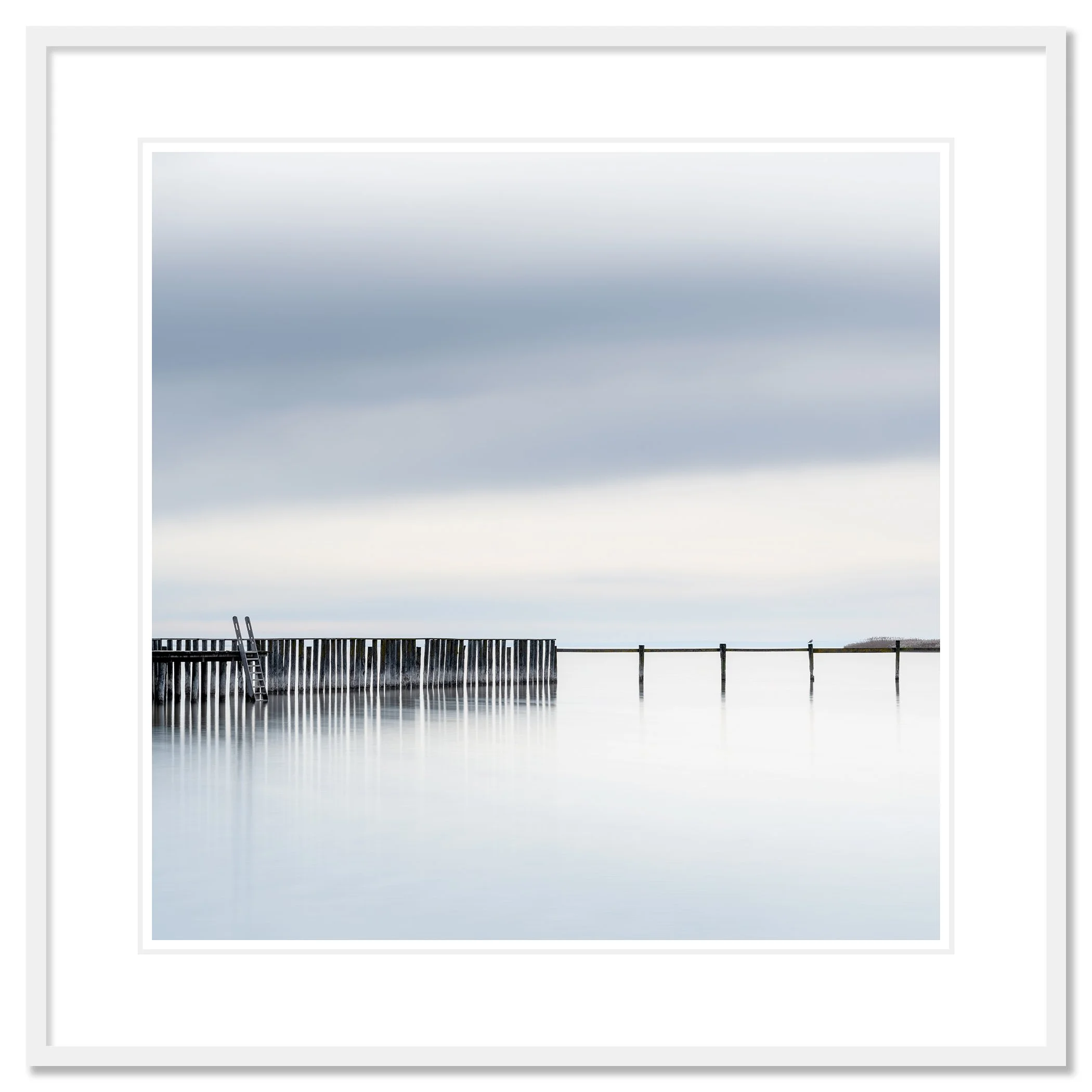 Gerald Berghammer - Color long exposure waterscape Photography. A pier extending into calm water with a ladder leaning against the side, under a cloudy sky. Classic framed white