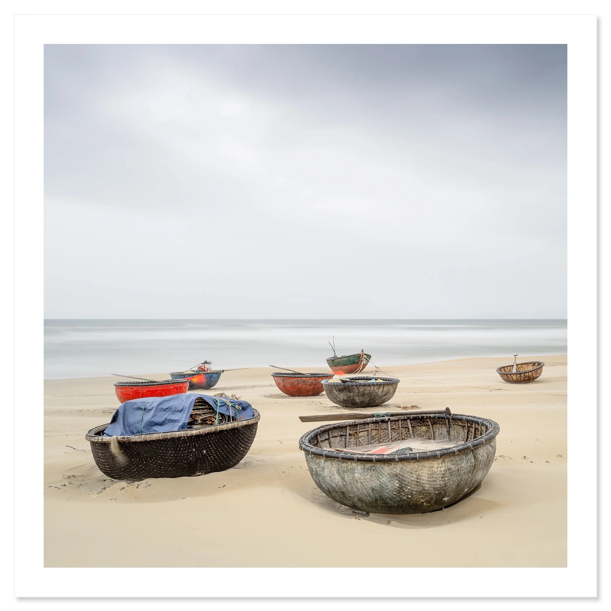 Gerald Berghammer - Color landscape photography. Several small boats resting on a sandy beach with calm ocean water under an overcast sky. Fine art print only