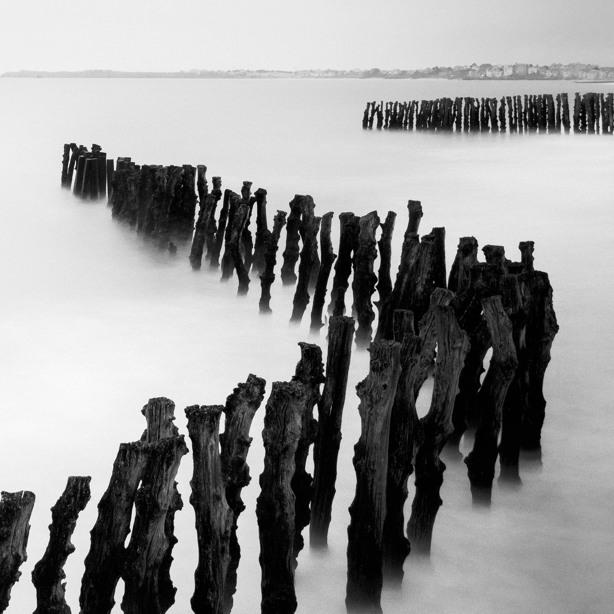 Close-up of Sea Breakers showing sculptural weathered timber groynes in smooth long-exposure water by Gerald Berghammer.