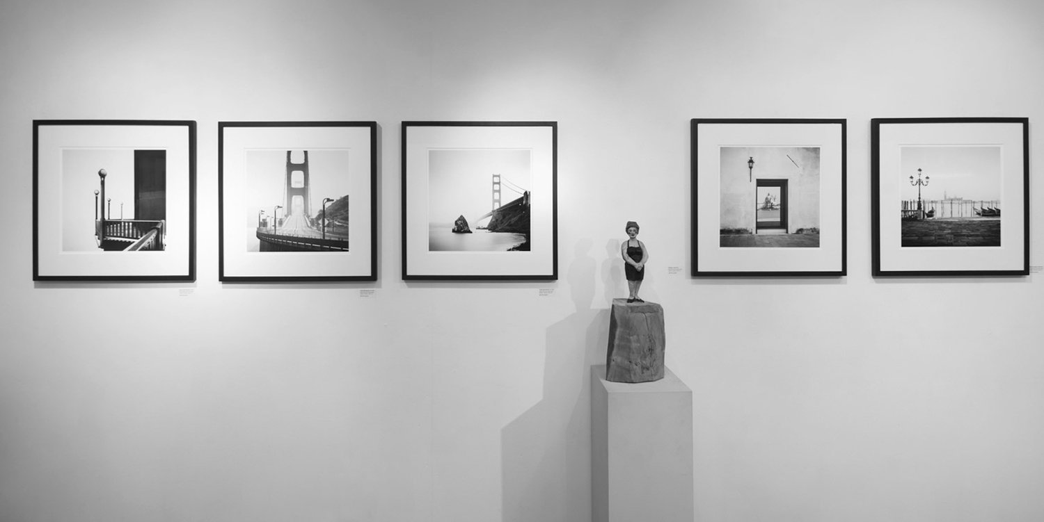 Five framed black-and-white photographs by Gerald Berghammer featuring the Golden Gate Bridge and Venetian architecture, displayed at the BLACK AND WHITE exhibition in Munich, 2017.