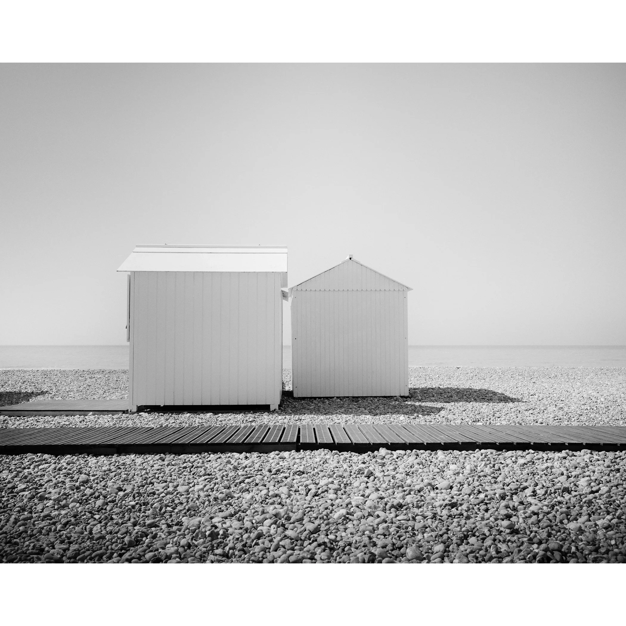 Esplanade Study 2 by Gerald Berghammer, minimalist black-and-white fine art photograph of two beach huts on the French coast.