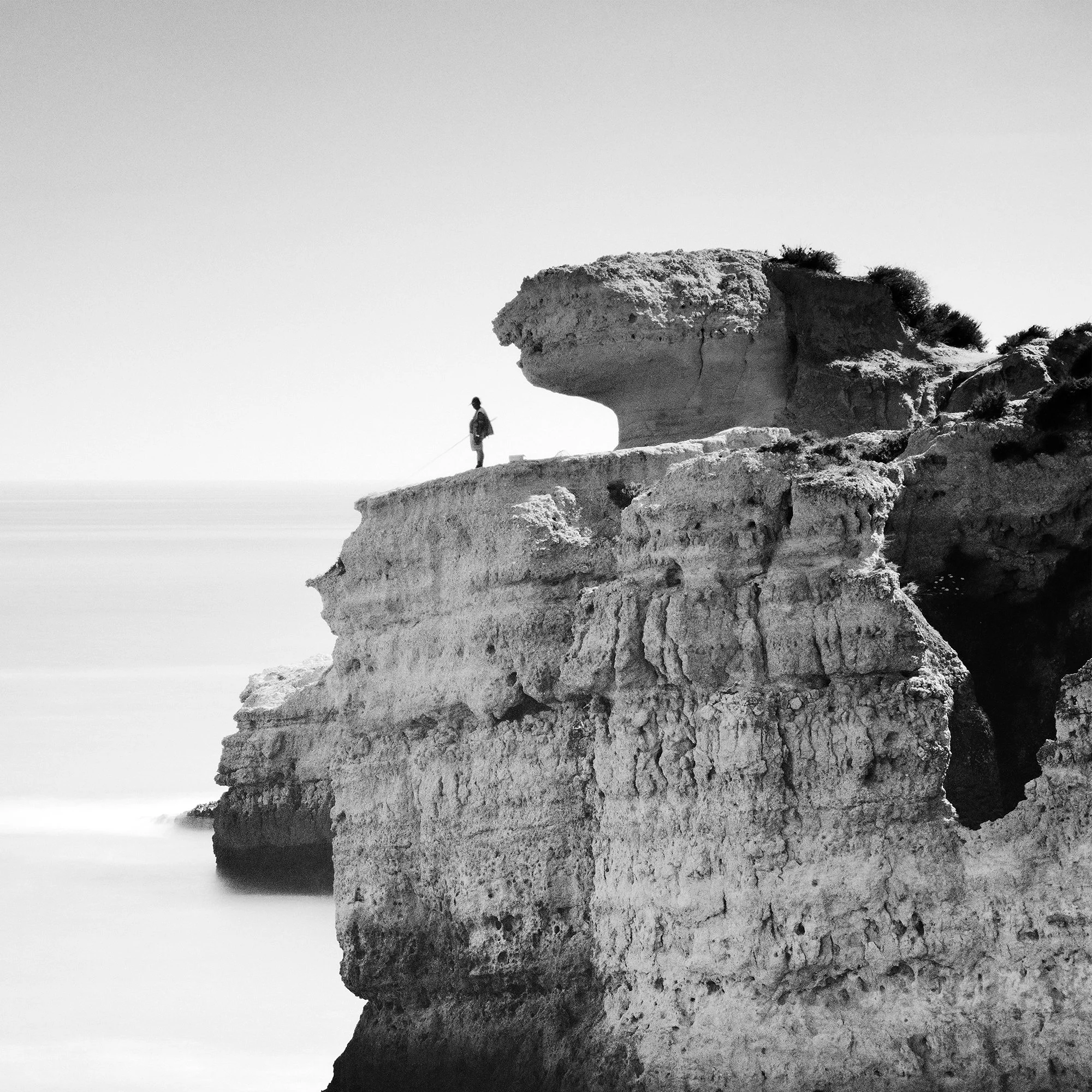 Cropped detail of Rock Fishing Study 1 showing layered cliff textures and the smooth long-exposure sea. Photo by Gerald Berghammer.