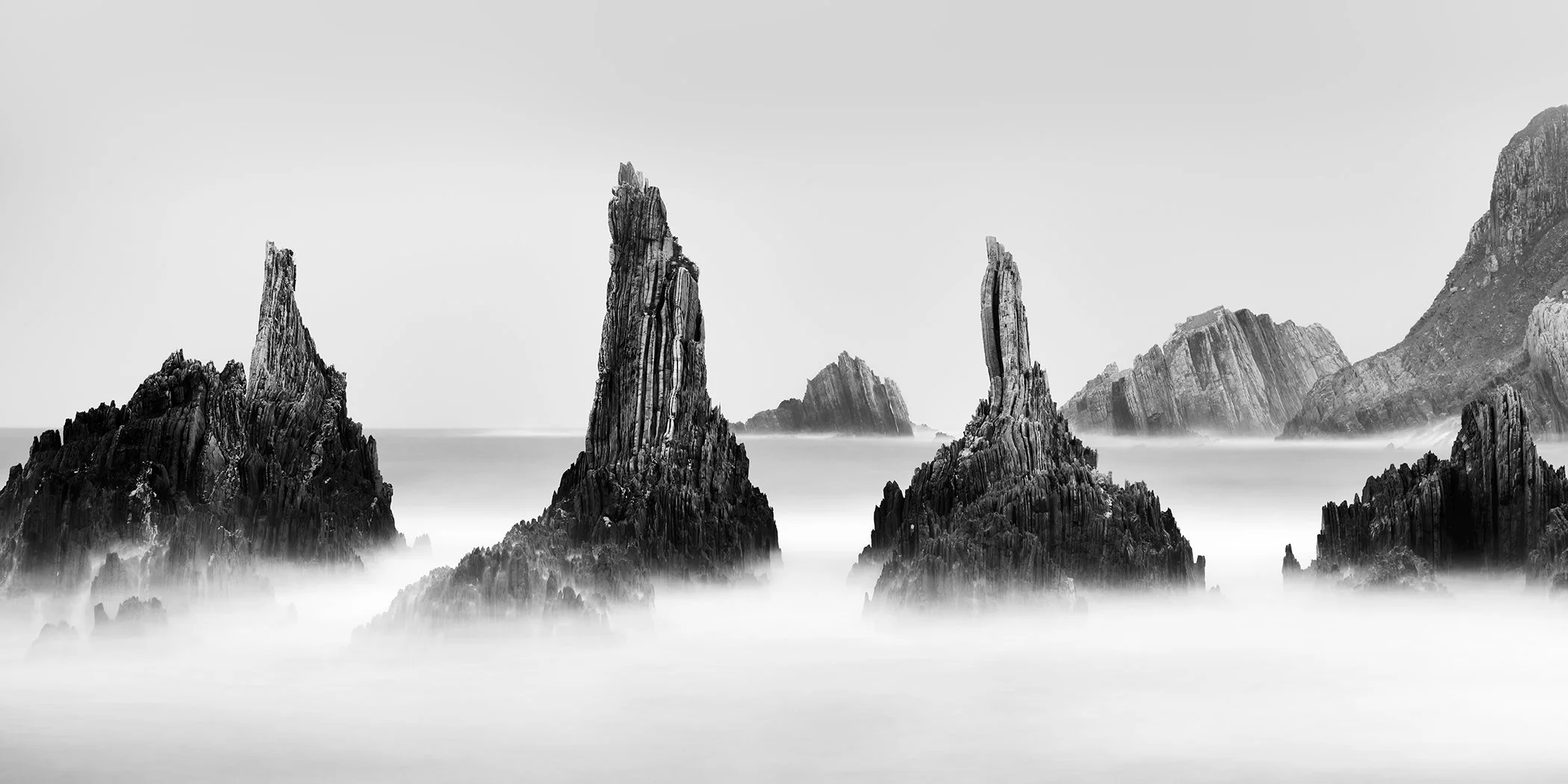 Rocky Peaks Panorama Study 5 by Gerald Berghammer, black-and-white long-exposure seascape of jagged Atlantic rock formations in Spain.