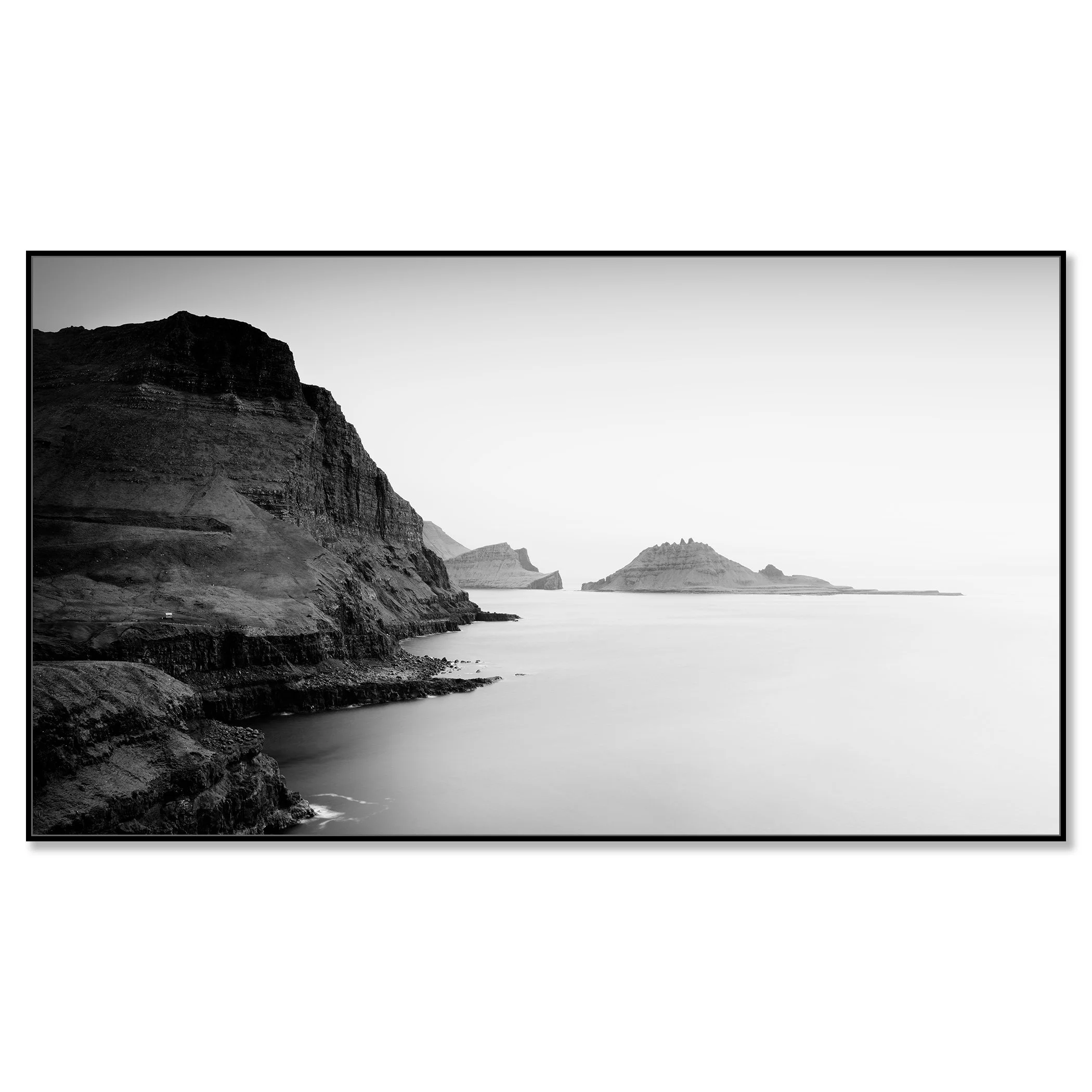 Black and white coastal landscape with steep cliffs and small rocky islands in calm sea – framed ArtBox black