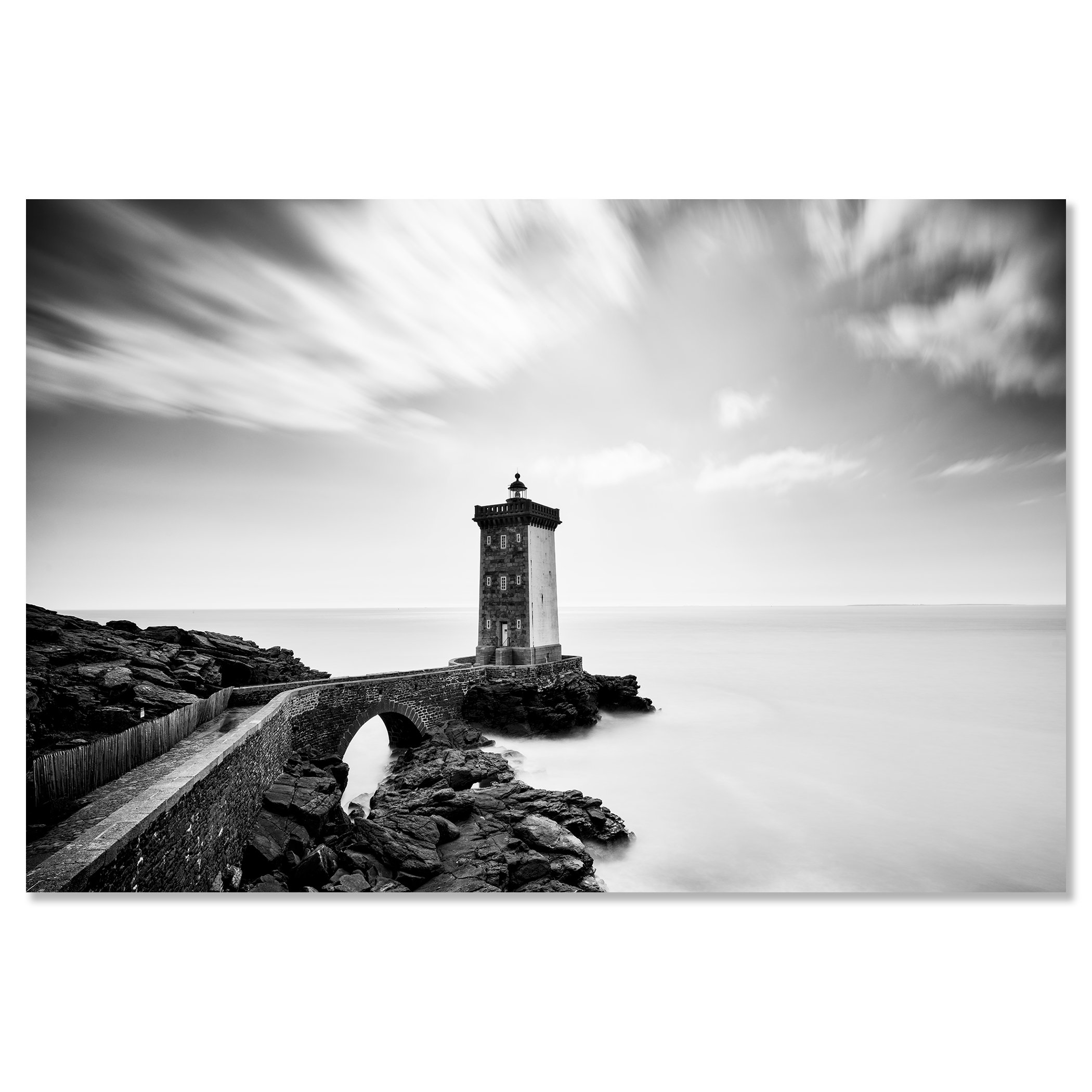 Black-and-white coastal lighthouse with stone bridge across rocks and overcast sky – dibond frameless