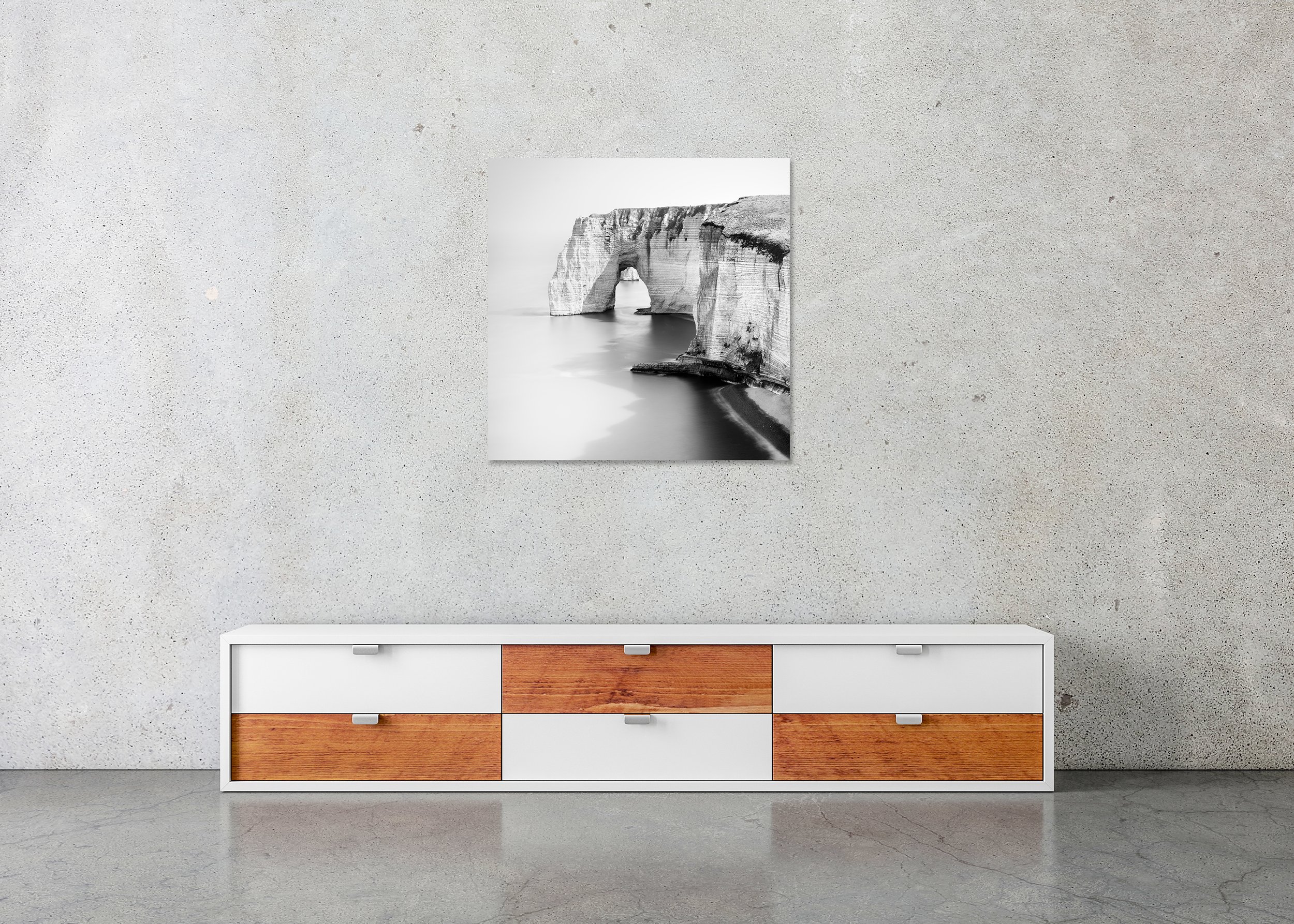 Frameless ChromaLuxe metal print showing a black and white photo of a rugged coastline with a natural rock arch above the water.