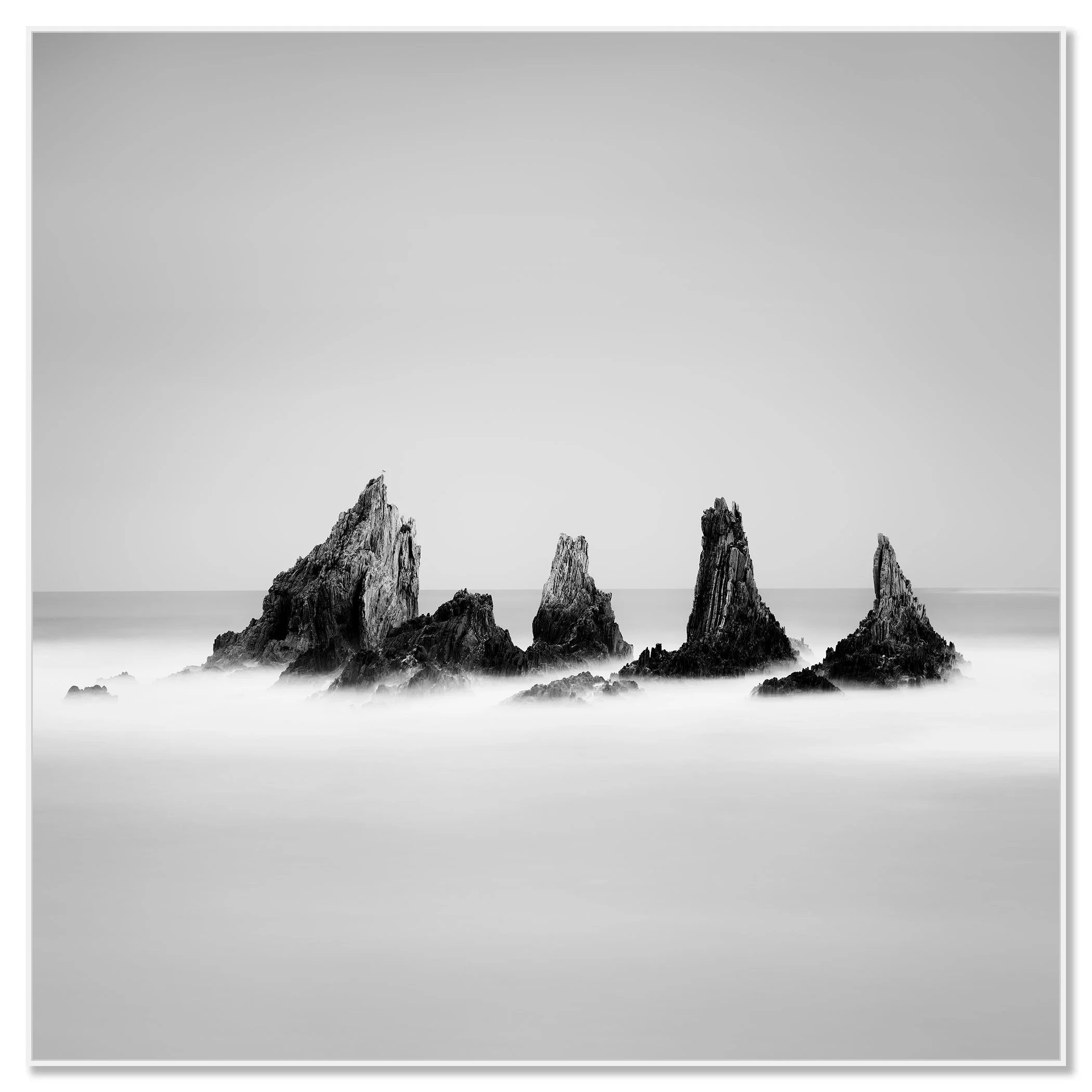 Rocky Peaks Study 1 by Gerald Berghammer, black-and-white seascape of sea stacks in Spain, mounted on aluminium Dibond in a white ArtBox frame.