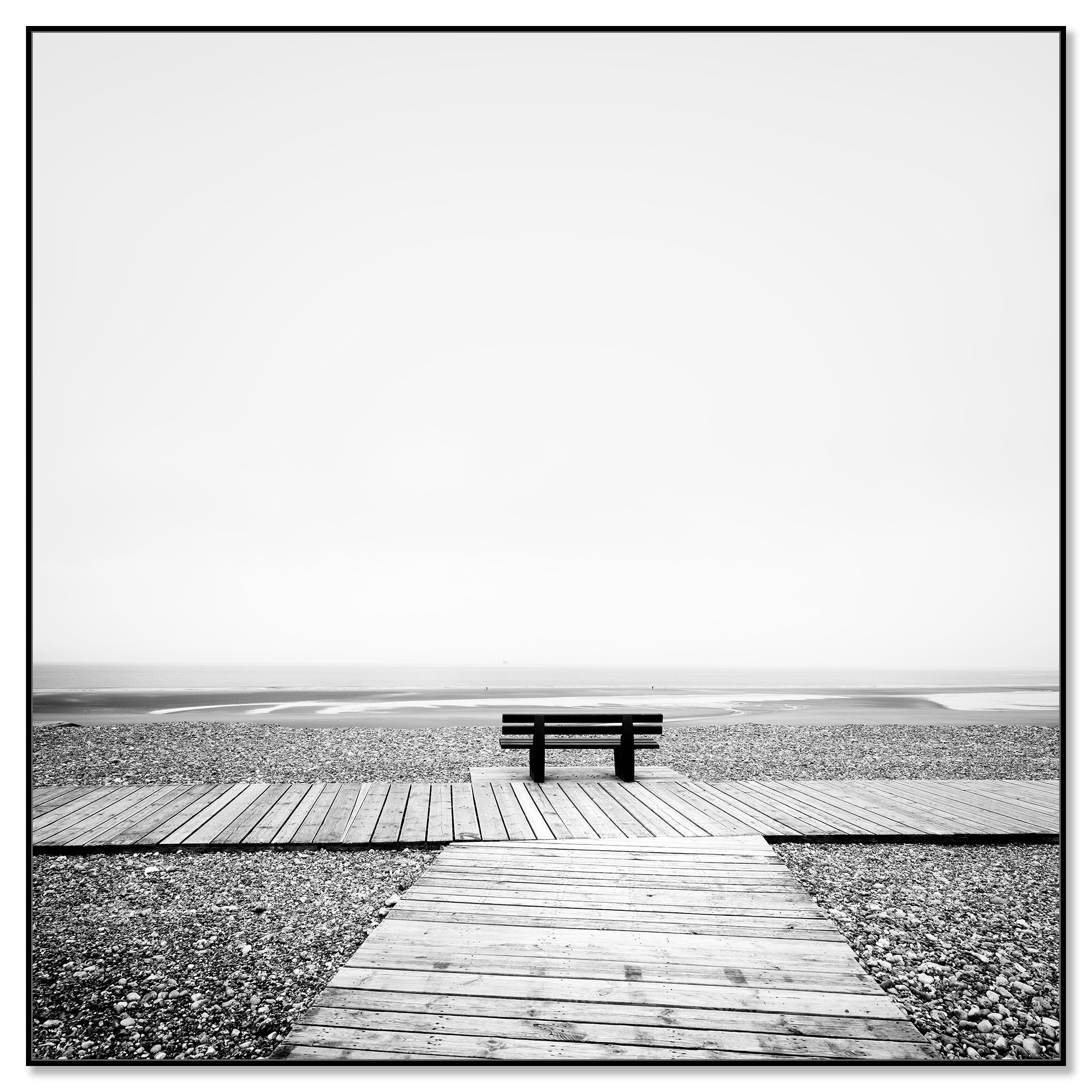 Wooden boardwalk and bench overlooking the Atlantic Ocean in black and white, with calm water and rocky shore – framed ArtBox black