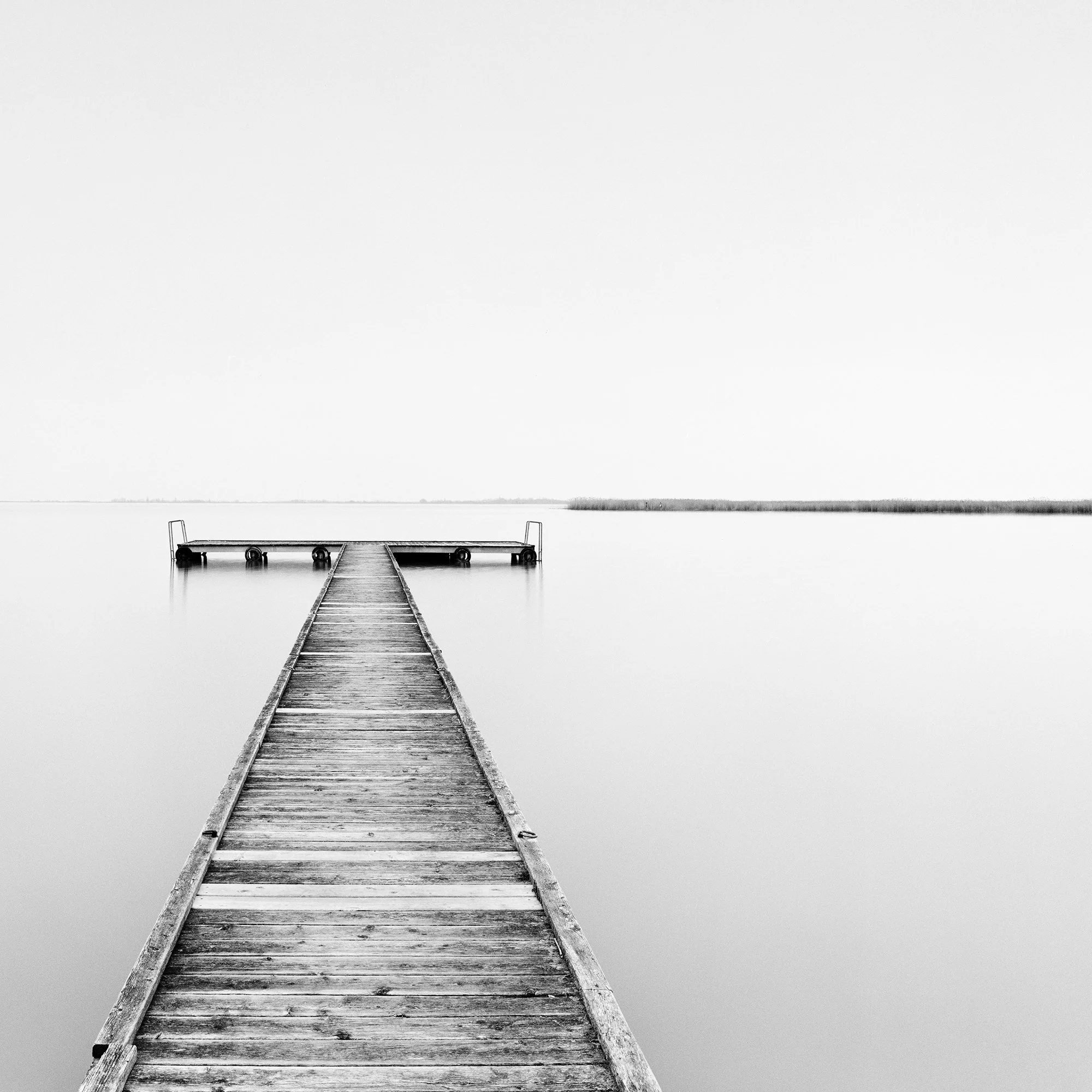 Detailed view of Pier Study 1 showing the wooden pier, negative space and distant shoreline by Gerald Berghammer.
