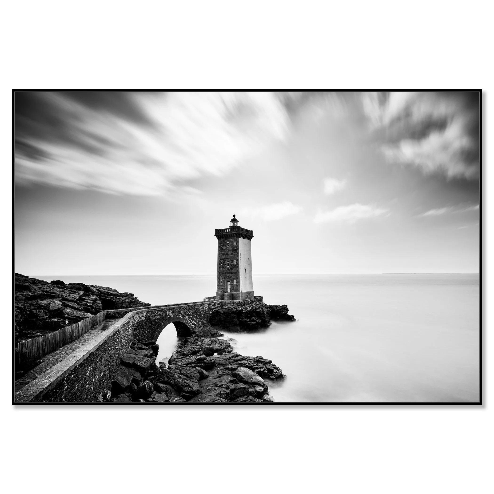 Black-and-white coastal lighthouse with stone bridge across rocks and overcast sky – framed ArtBox black