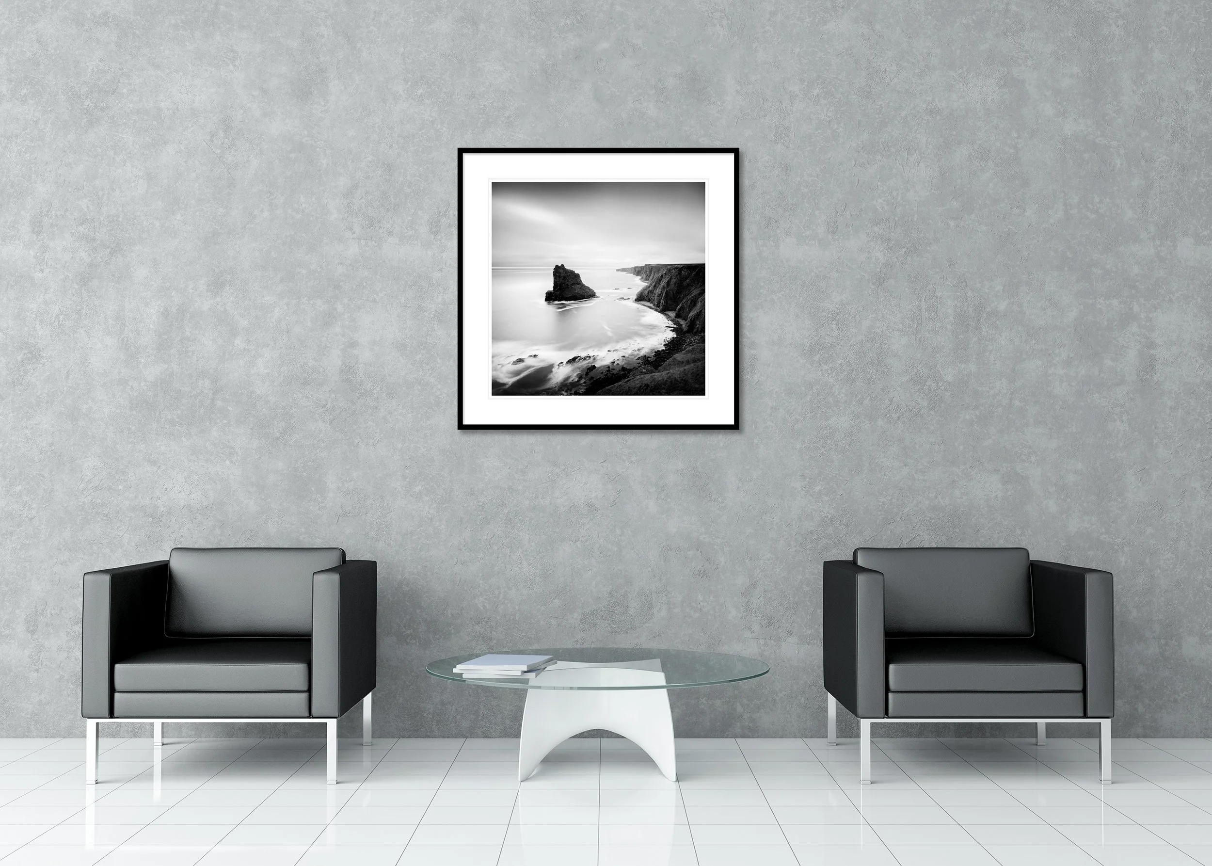Black-and-white long-exposure coastal cliffs with a solitary sea stack in calm ocean waters; archival pigment print in a classic frame with mount.