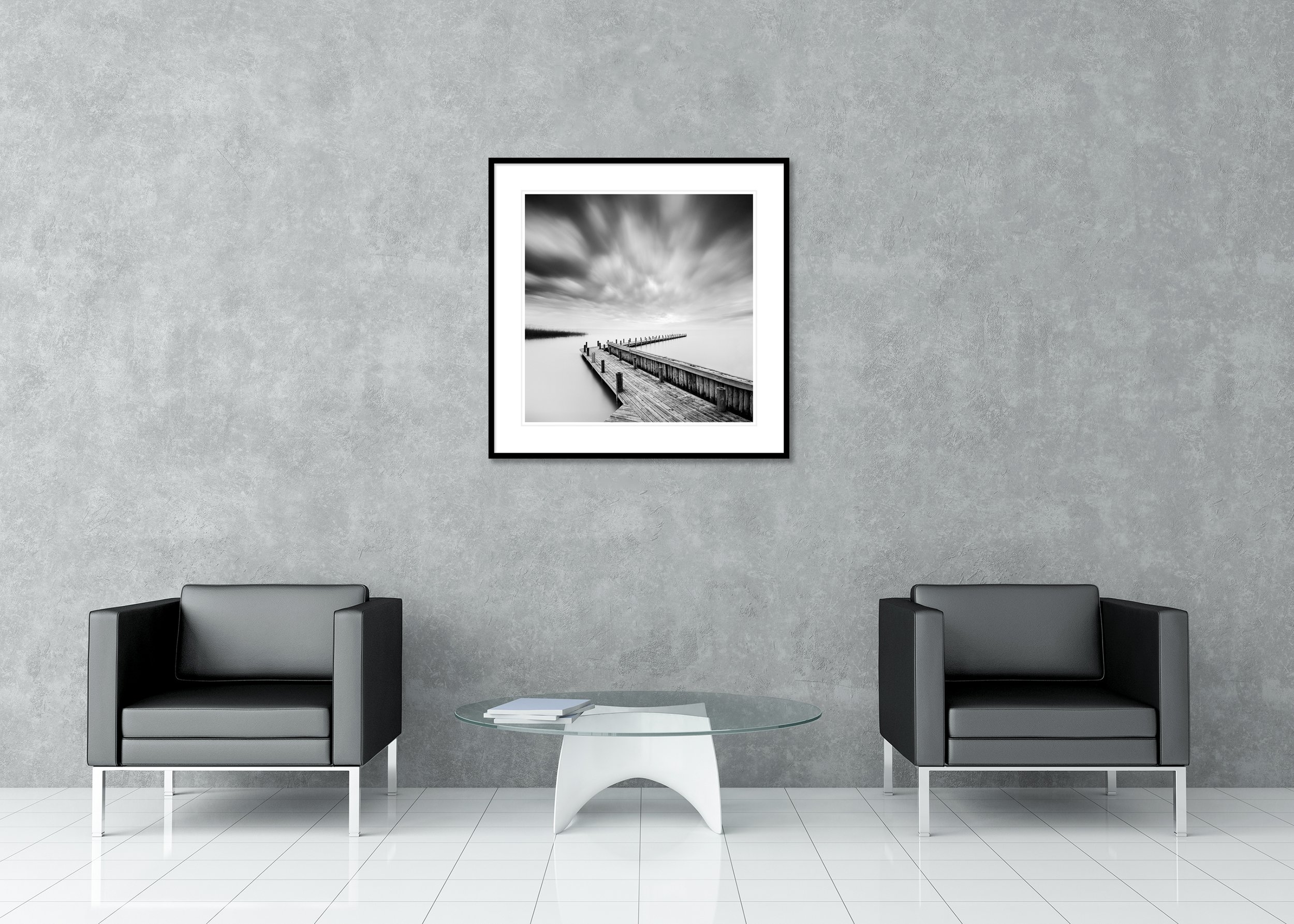 Black and white fine art photo of a wooden pier leading into a calm lake under dramatic clouds, archival pigment print in a classic frame with mount