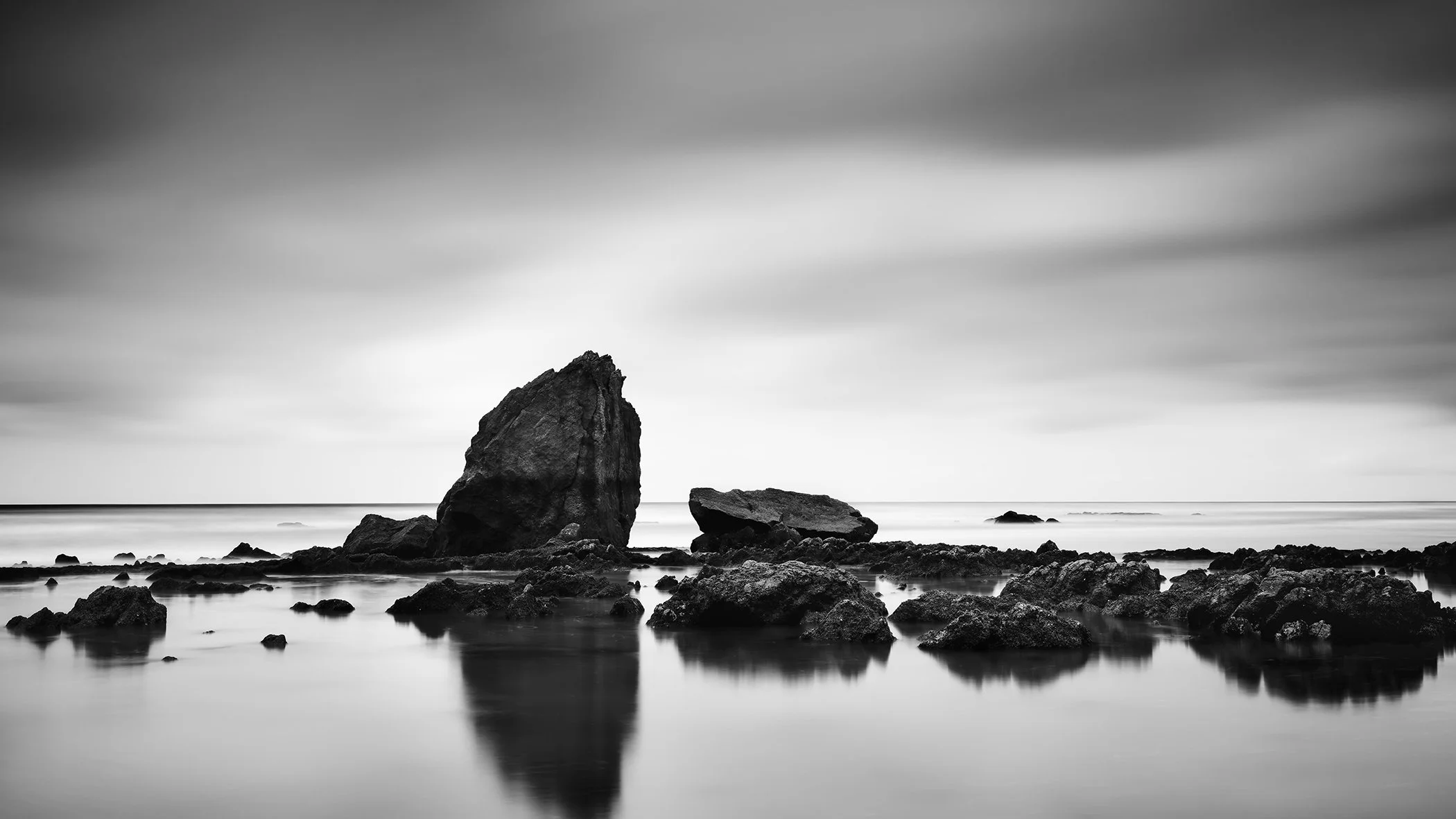 Beach Rock Panorama Study 2 – France, panoramic black-and-white seascape with coastal rock formations and long-exposure water by Gerald Berghammer