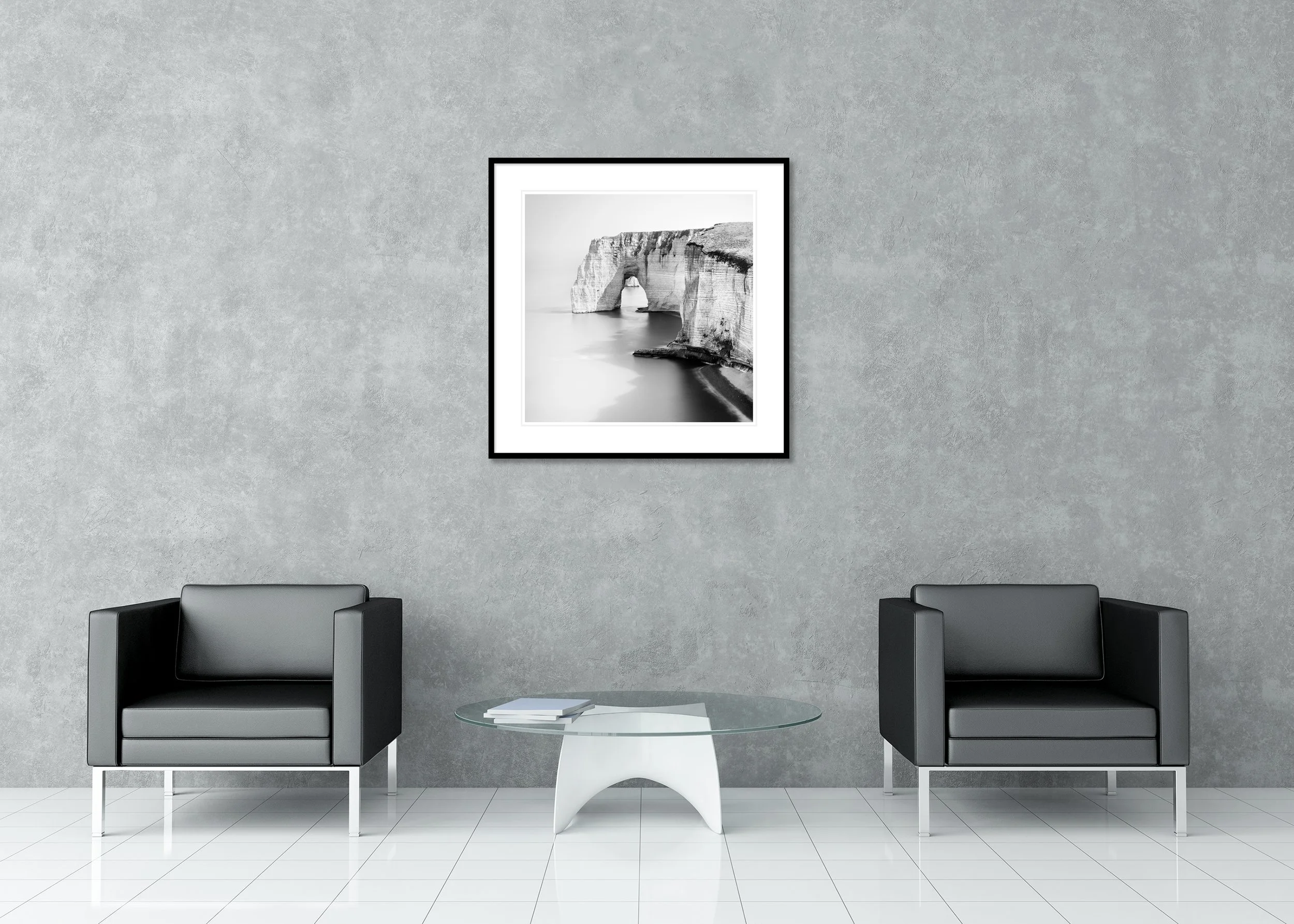Black and white archival pigment print of a rugged coastline with a natural rock arch above the water, presented in a classic frame with a mount