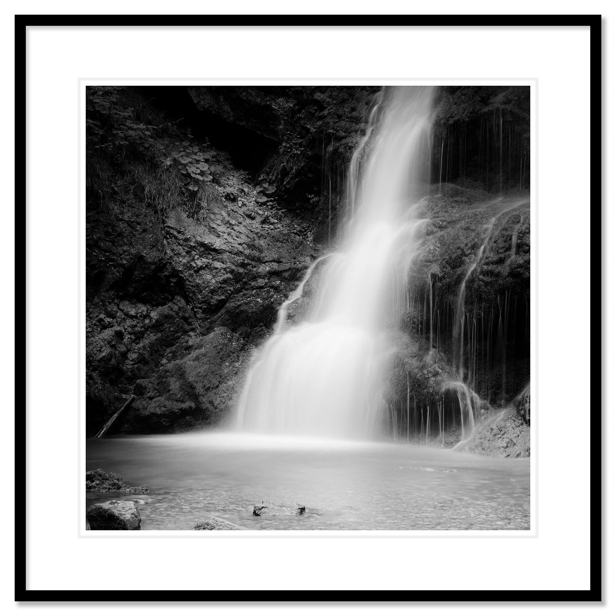 © 2020 Gerald Berghammer - Black and white long exposure abstract photography.  Waterfall descending into a calm pool surrounded by rocky terrain. Classic framed black