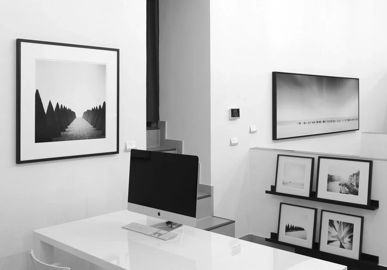 Two framed black-and-white photographs by Gerald Berghammer, showing a winding desert road and birch woodland at ART AFFAIR II in Vienna.