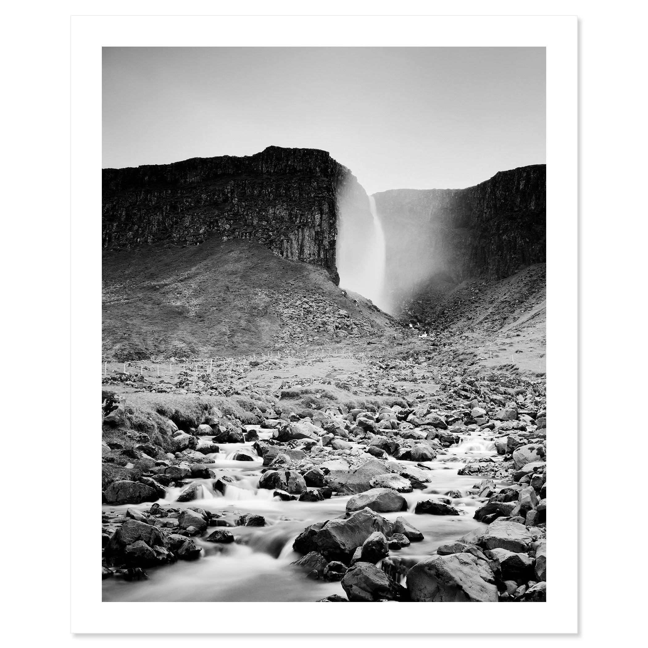 Gerald Berghammer - Black and white landscape photography. A waterfall cascading down a rocky cliff into a stream surrounded by rocks and rugged terrain. Fine art print only
