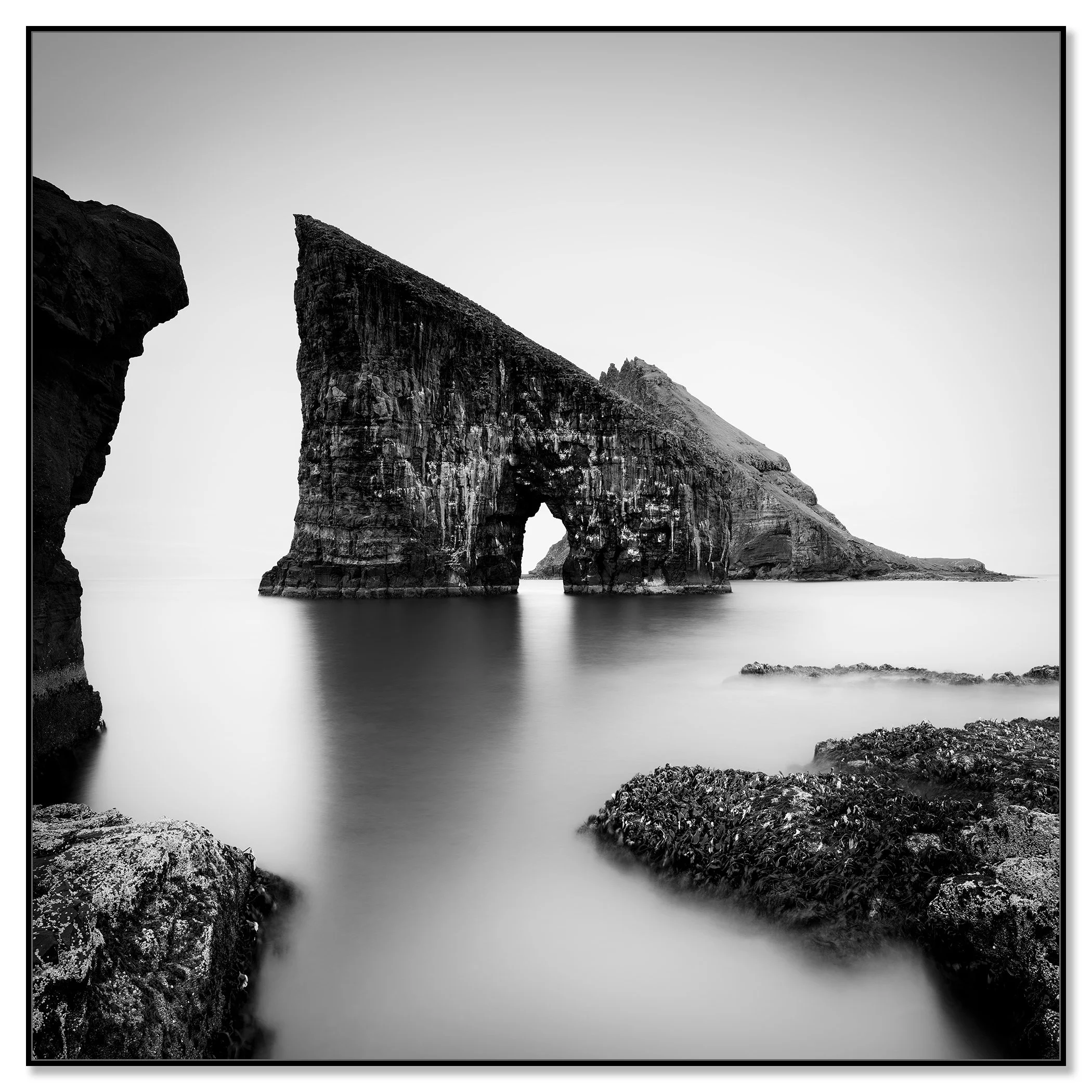 Black and white coastal landscape with a striking sea stack arch and soft long-exposure water – dibond ArtBox black