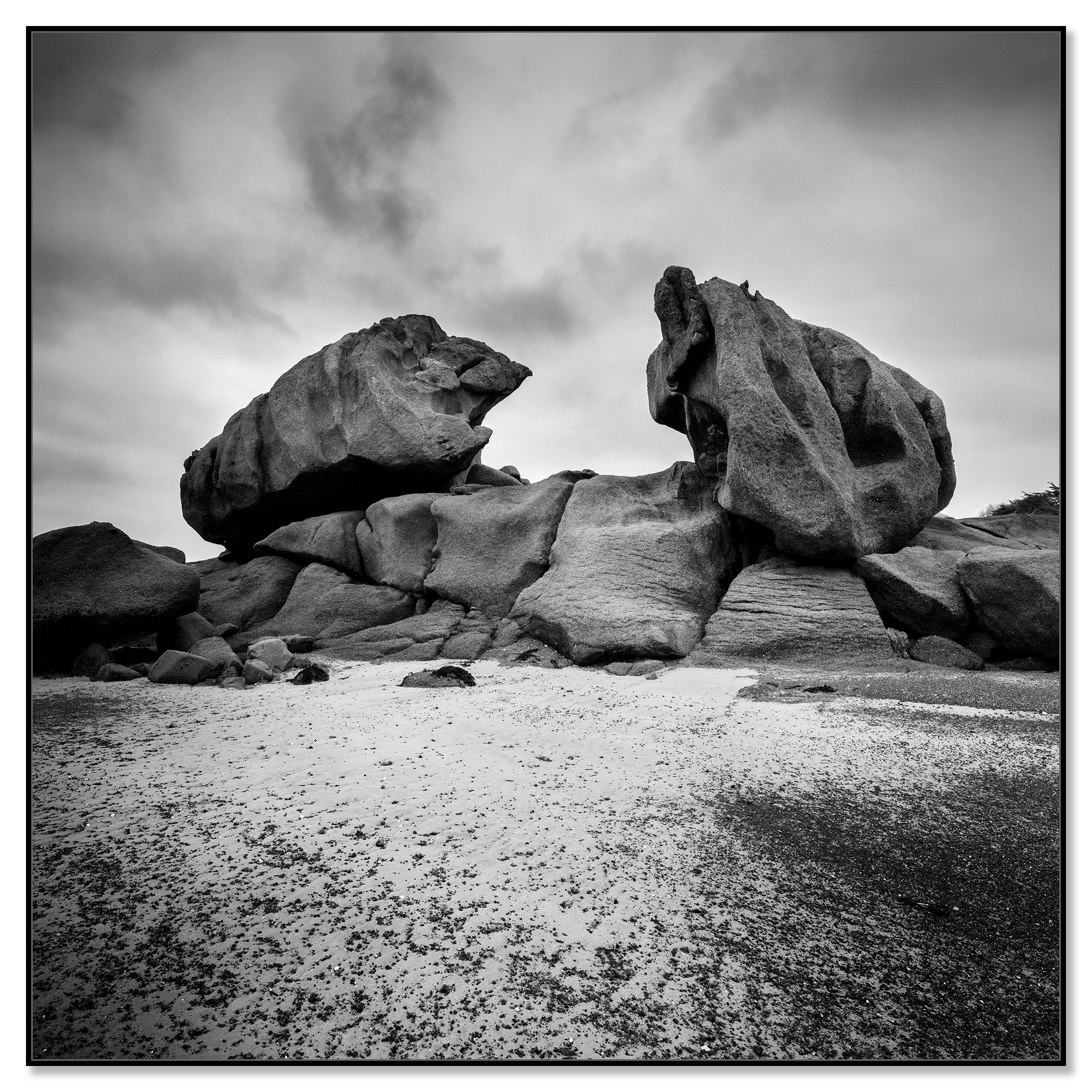 Monochrome coastal landscape with giant granite rocks and sandy beach along a rugged coast – framed ArtBox black