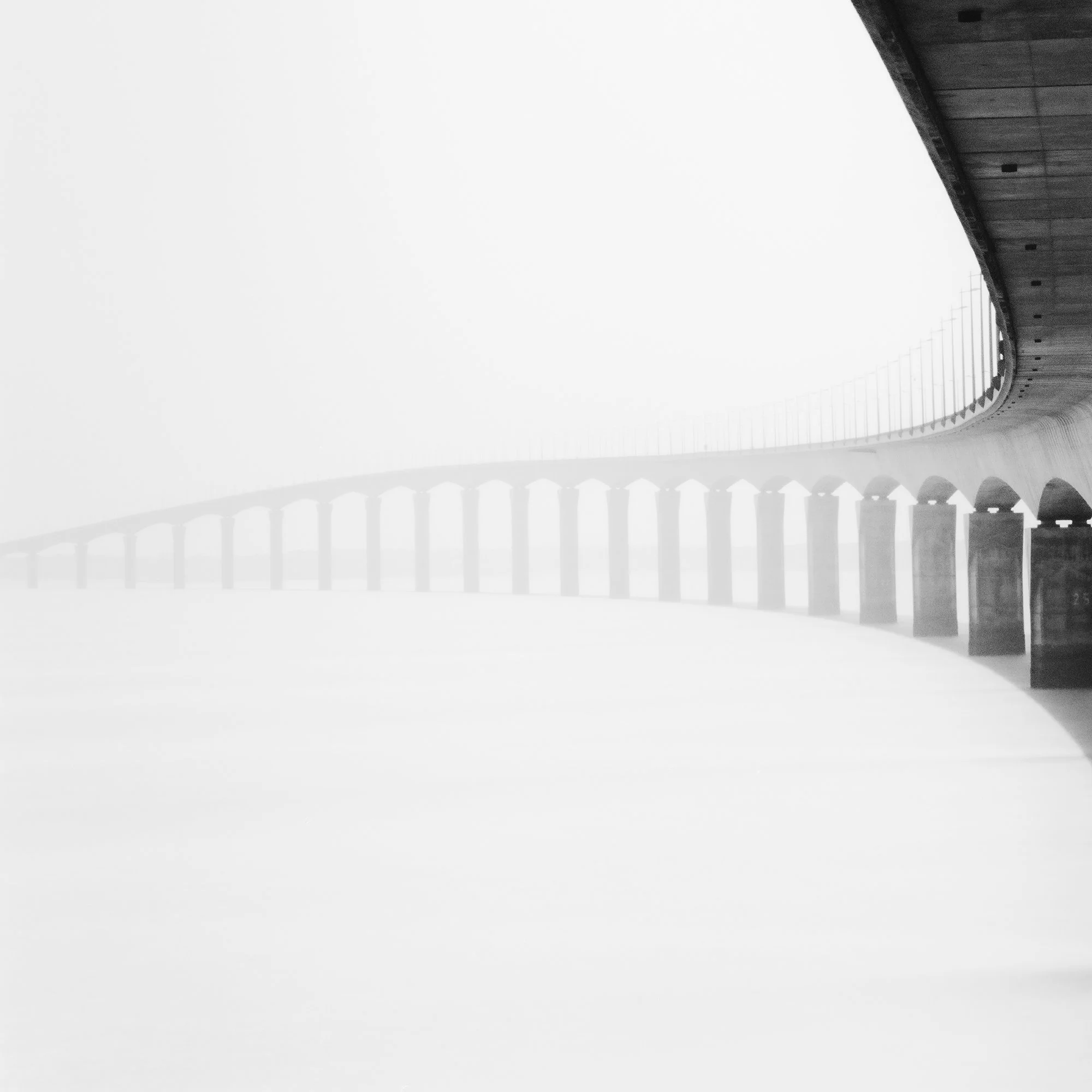 Île de Ré Bridge Study 1 – detail of the repeating bridge piers fading into dense mist in France by Gerald Berghammer.