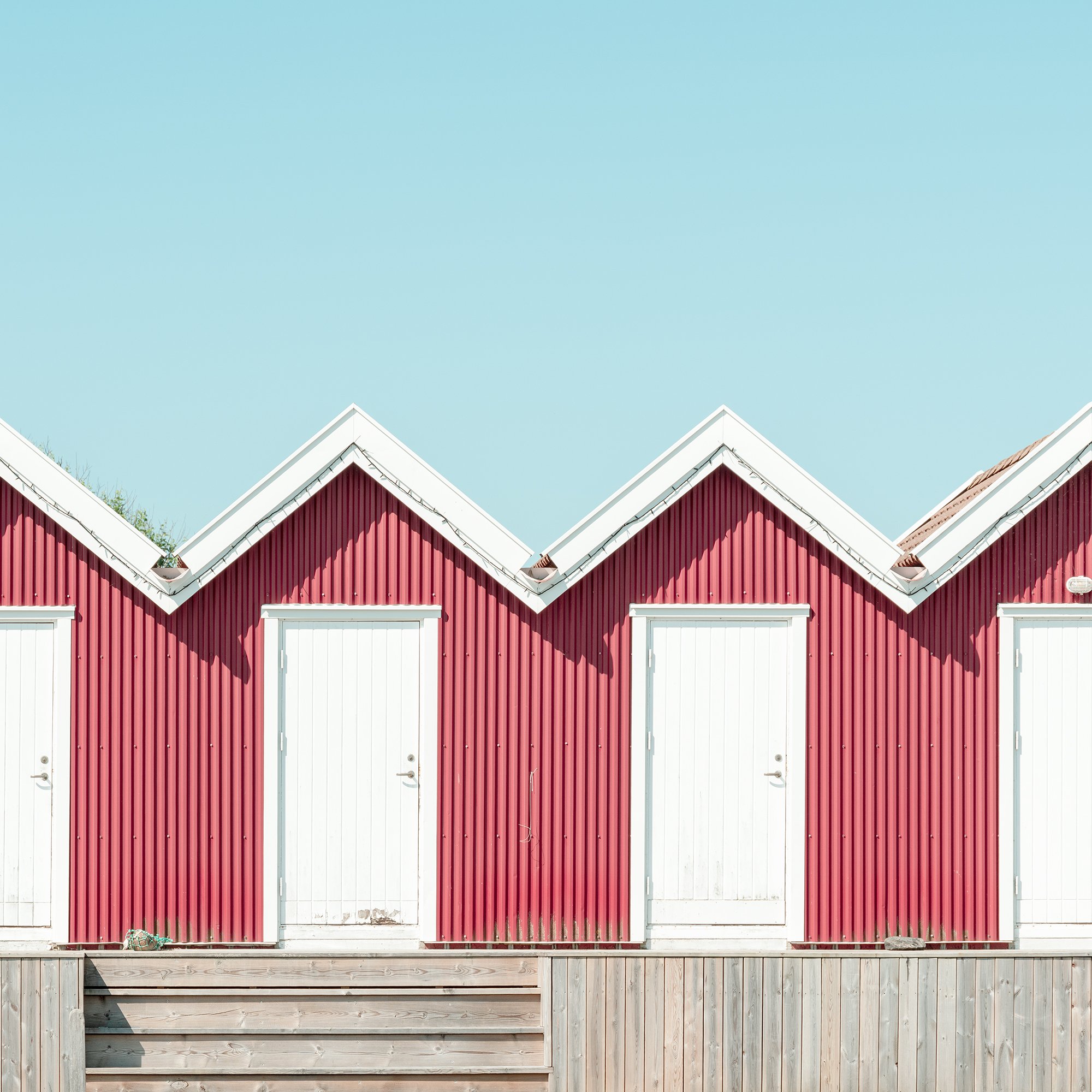 Close-up detail of Red Beach Huts Study 1 showing traditional red timber façades and white doors in Sweden.