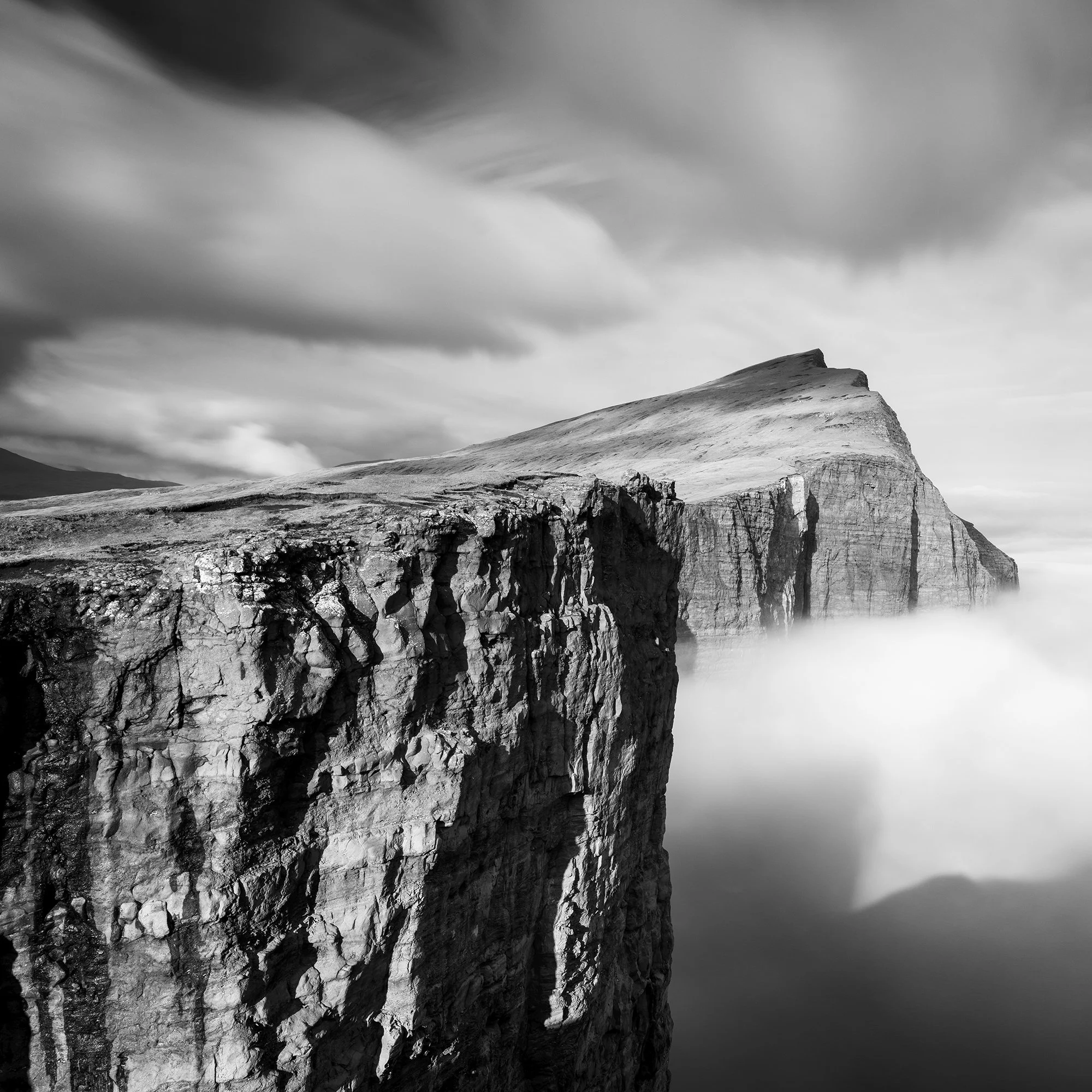 Detailed crop of Trælanípa’s rugged basalt cliffs beneath sweeping clouds, photographed by Gerald Berghammer.