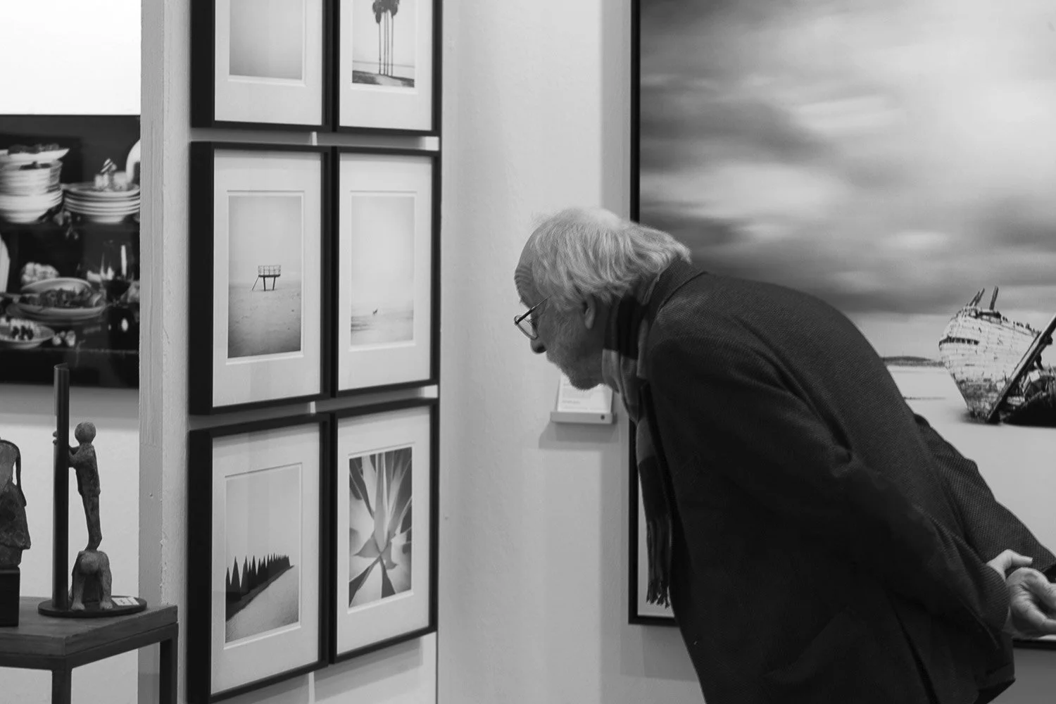 Elderly man viewing framed black-and-white photographs in a Paris fine art gallery, Silverfineart exhibition by Gerald Berghammer..