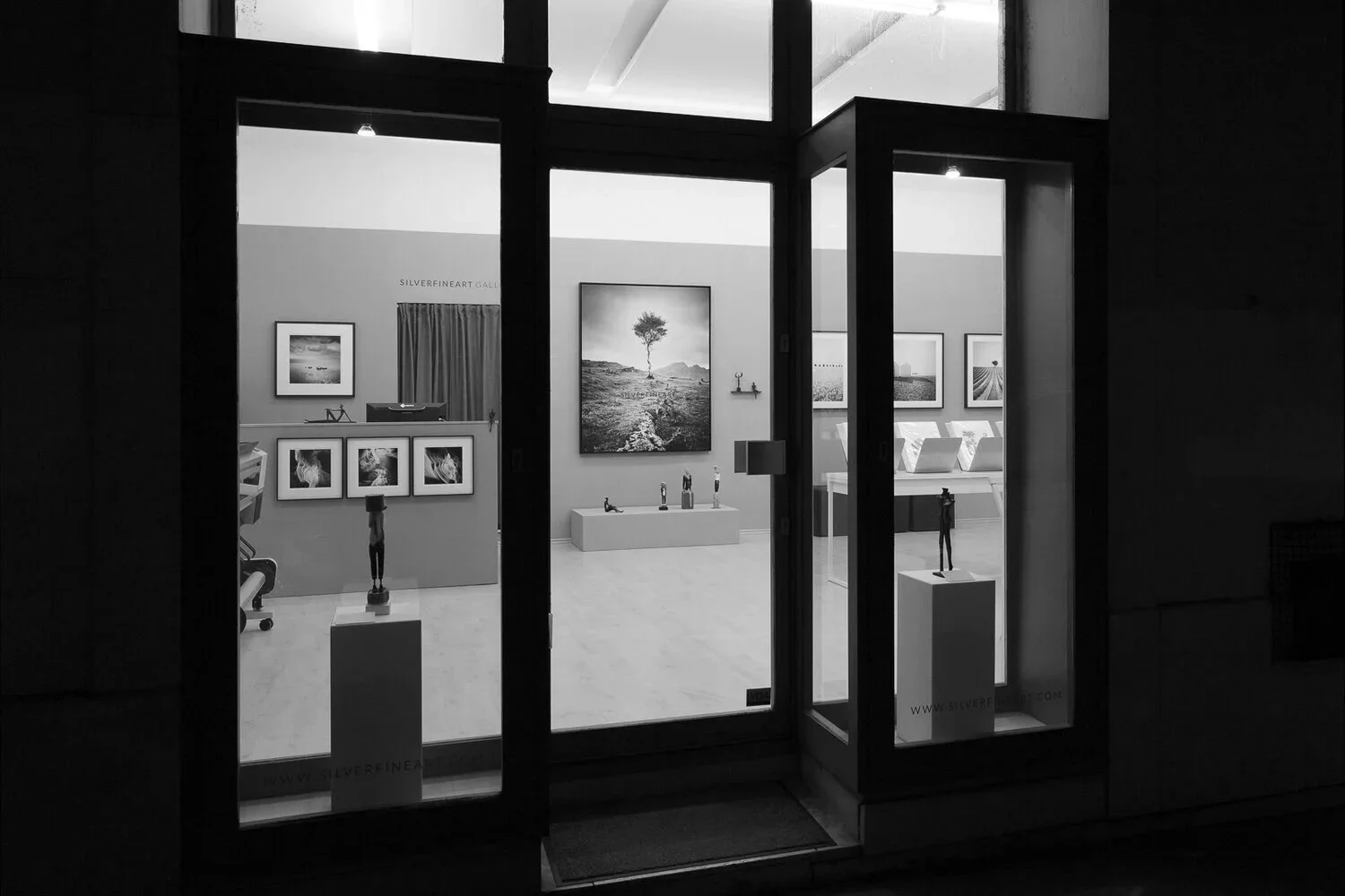Exterior view of SILVERFINEART Gallery in Vienna, showing photographs by Gerald Berghammer and sculptures through the windows.