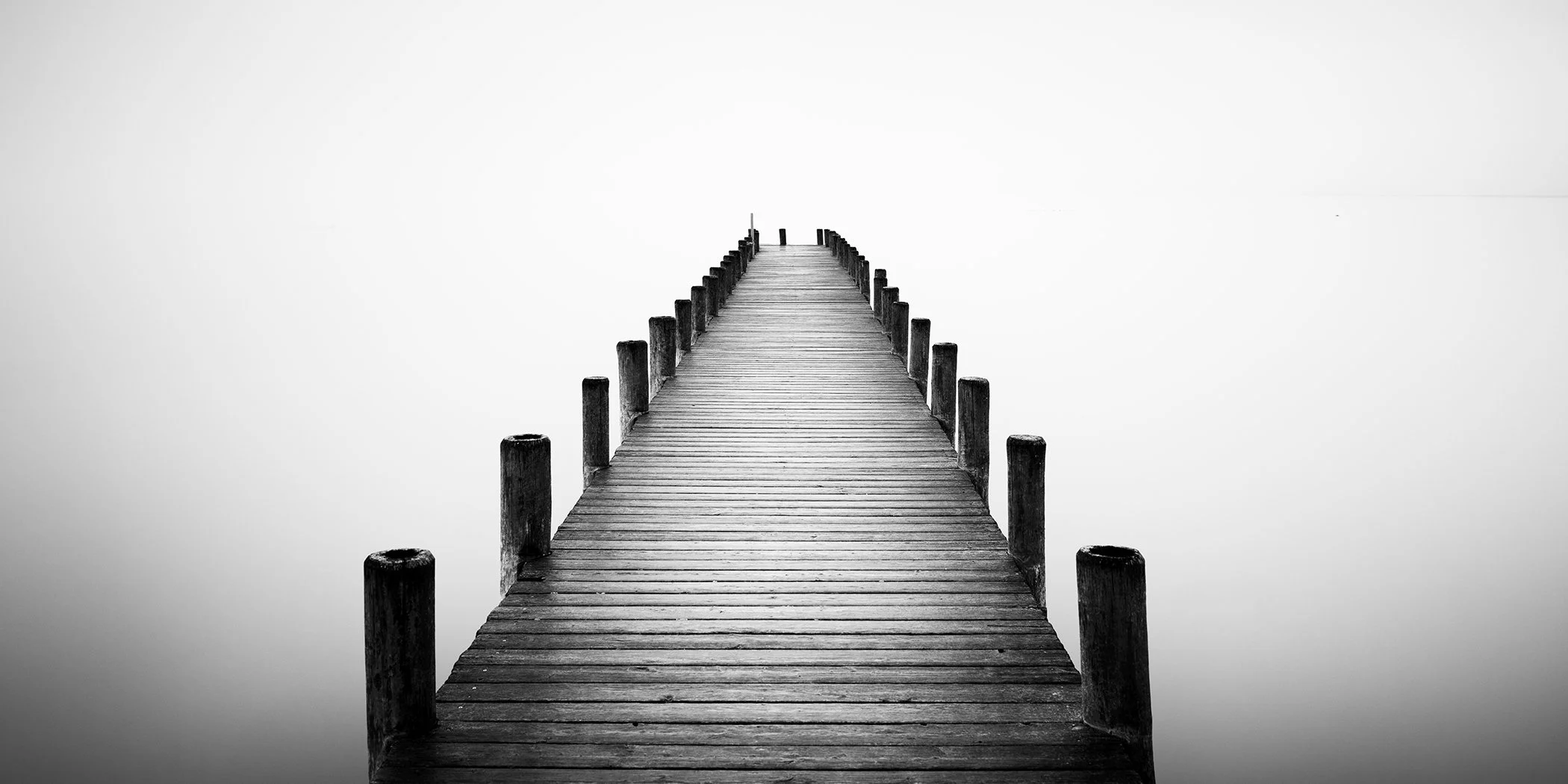 Solitary wooden pier in black and white with symmetrical perspective